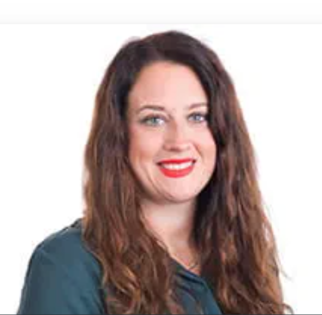 Professional headshot of a smiling woman with long brown hair and red lips wearing a teal top.