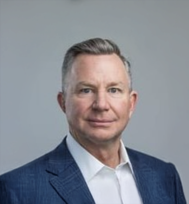 Professional headshot of a middle-aged businessman with gray hair wearing a navy blazer and white shirt.