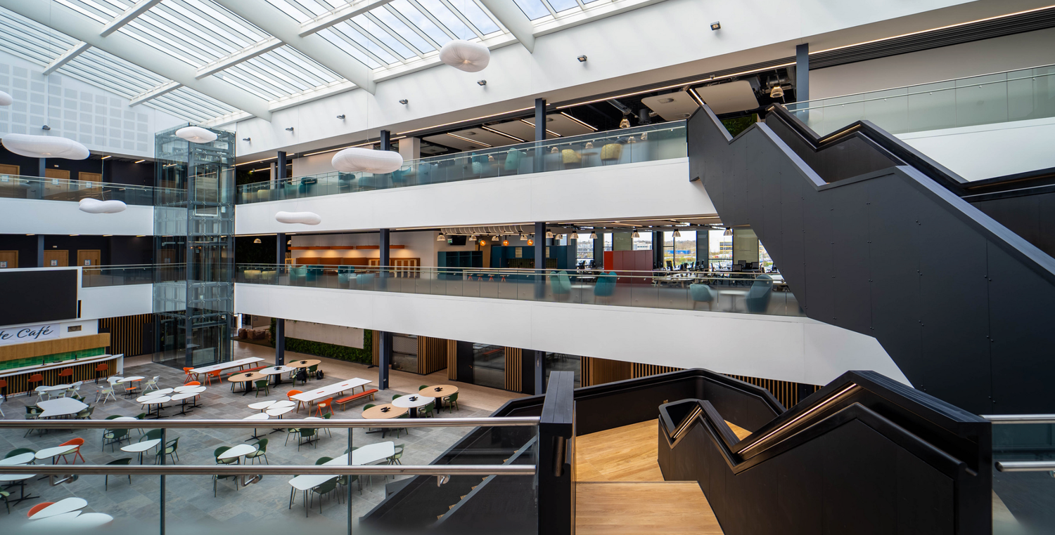 Modern multi-level atrium with glass railings, sleek staircases, and vintage aircraft displays in a contemporary museum.