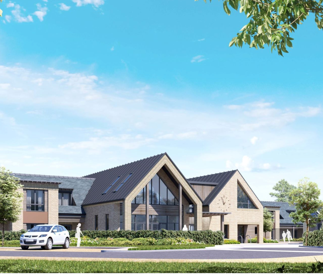Modern residential development with gabled rooflines, large glass windows, brick facade, and landscaped grounds under a bright blue sky.