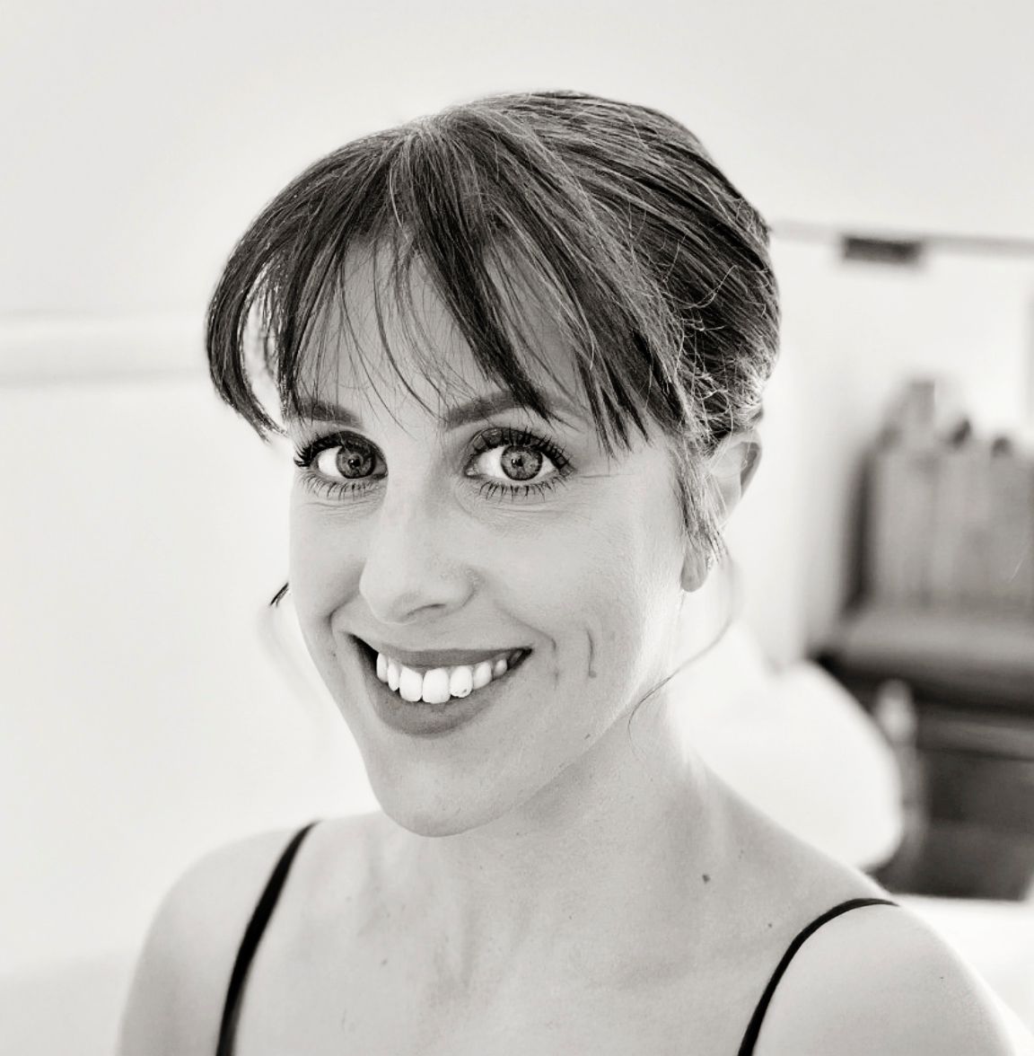 Smiling woman with dark hair and bright eyes in a black-and-white portrait photo.