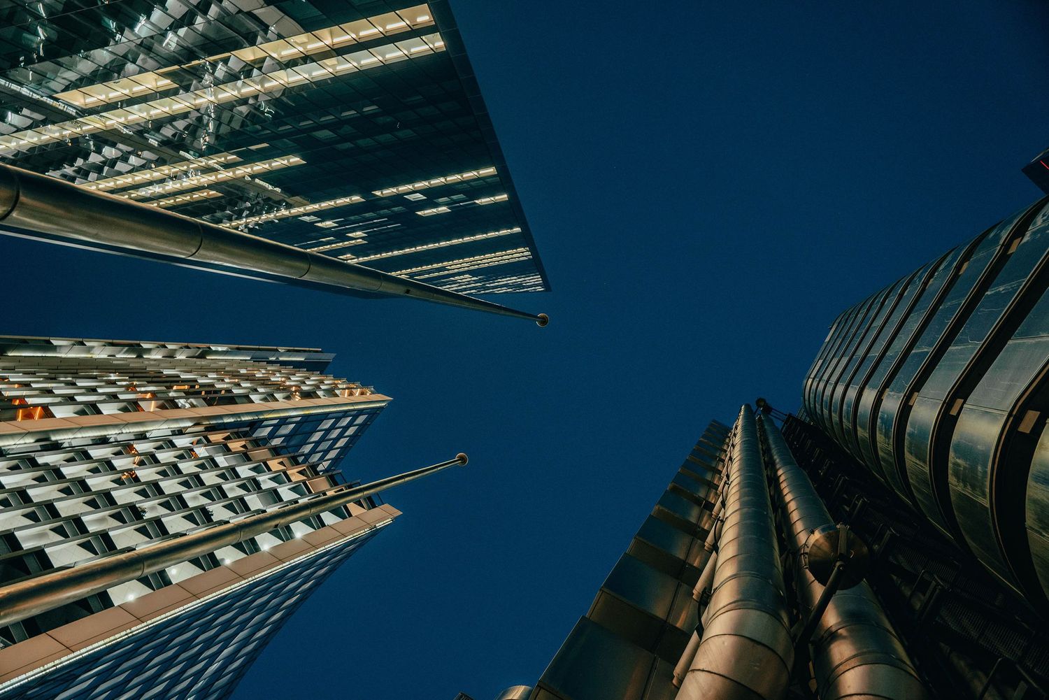 Low-angle view of modern skyscrapers reaching toward a clear blue sky in an urban financial district.
