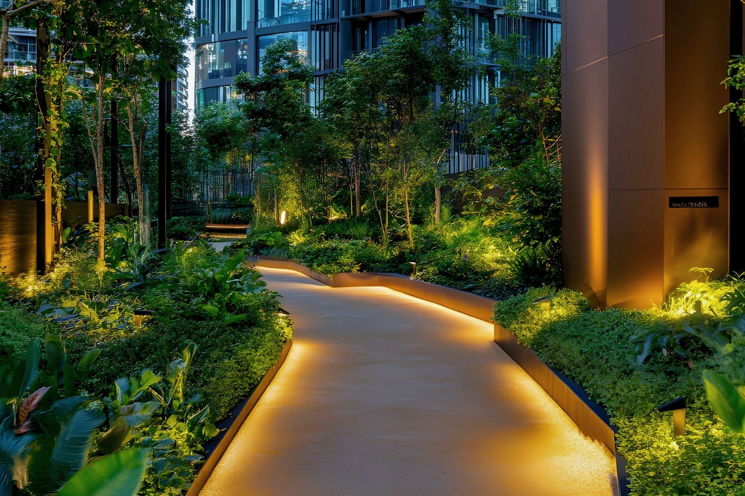 Illuminated garden pathway with lush tropical plants and warm LED lighting between modern residential buildings at dusk.