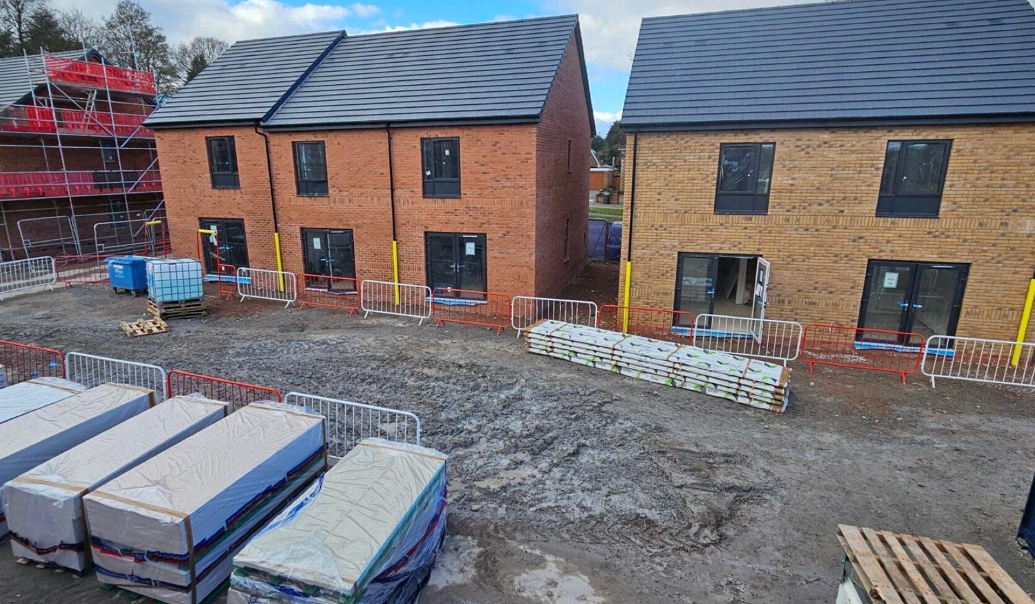 Solar panels installed on residential rooftops in a modern housing development under a blue sky.