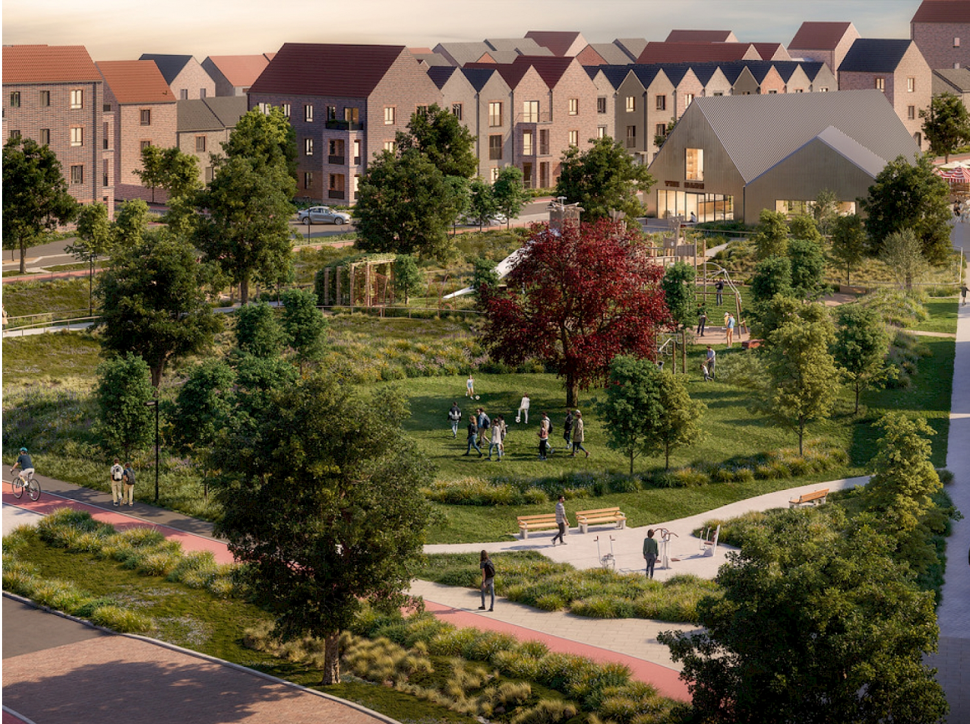 Aerial view of a modern residential development with lush green parkland, tree-lined paths, and townhouses at sunset.