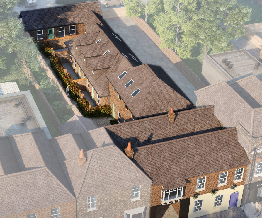 Aerial view of a modern residential development with brown rooftops surrounded by trees and greenery.