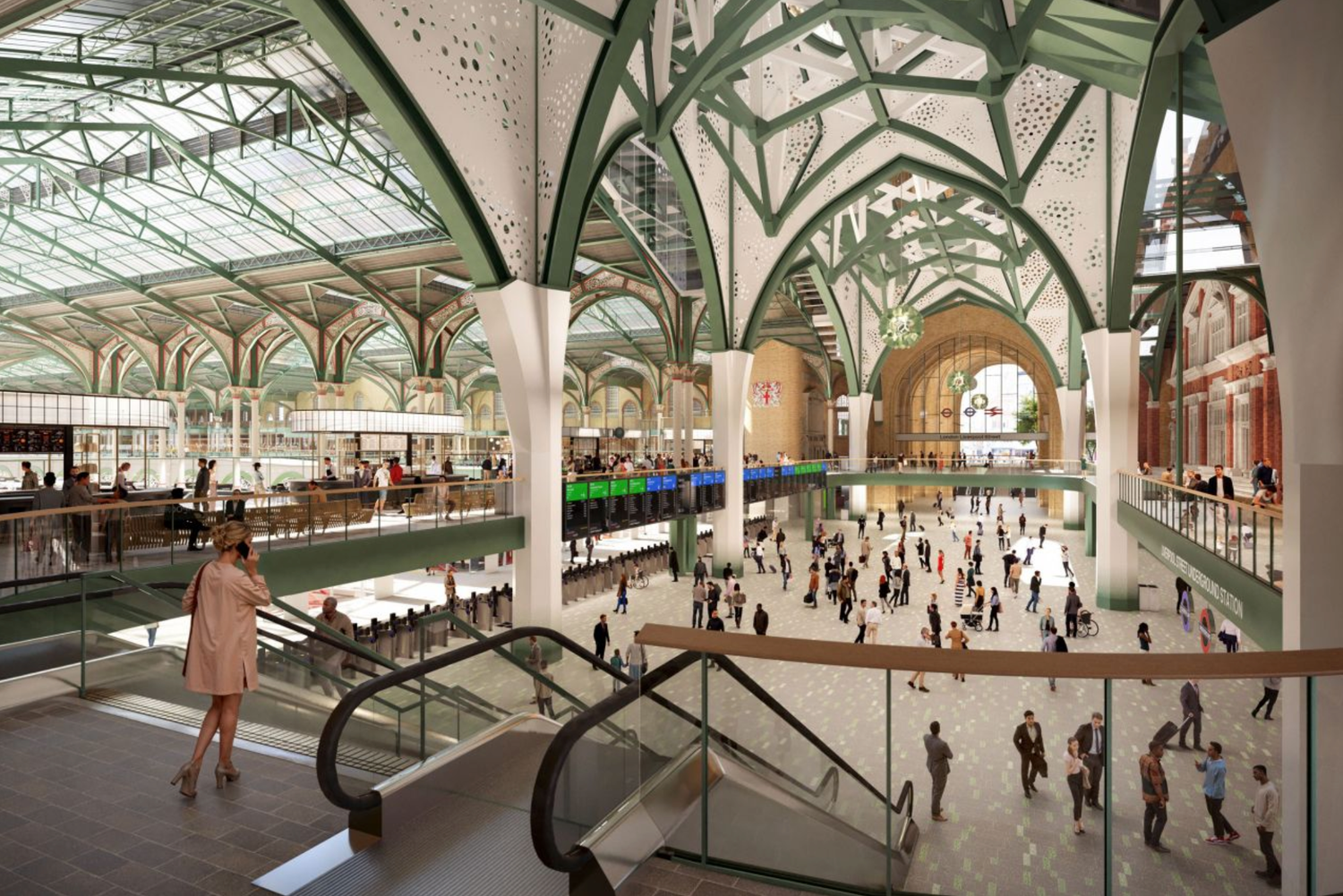 Grand train station interior with arched glass ceiling, ornate columns, escalators, and crowds of people walking through.