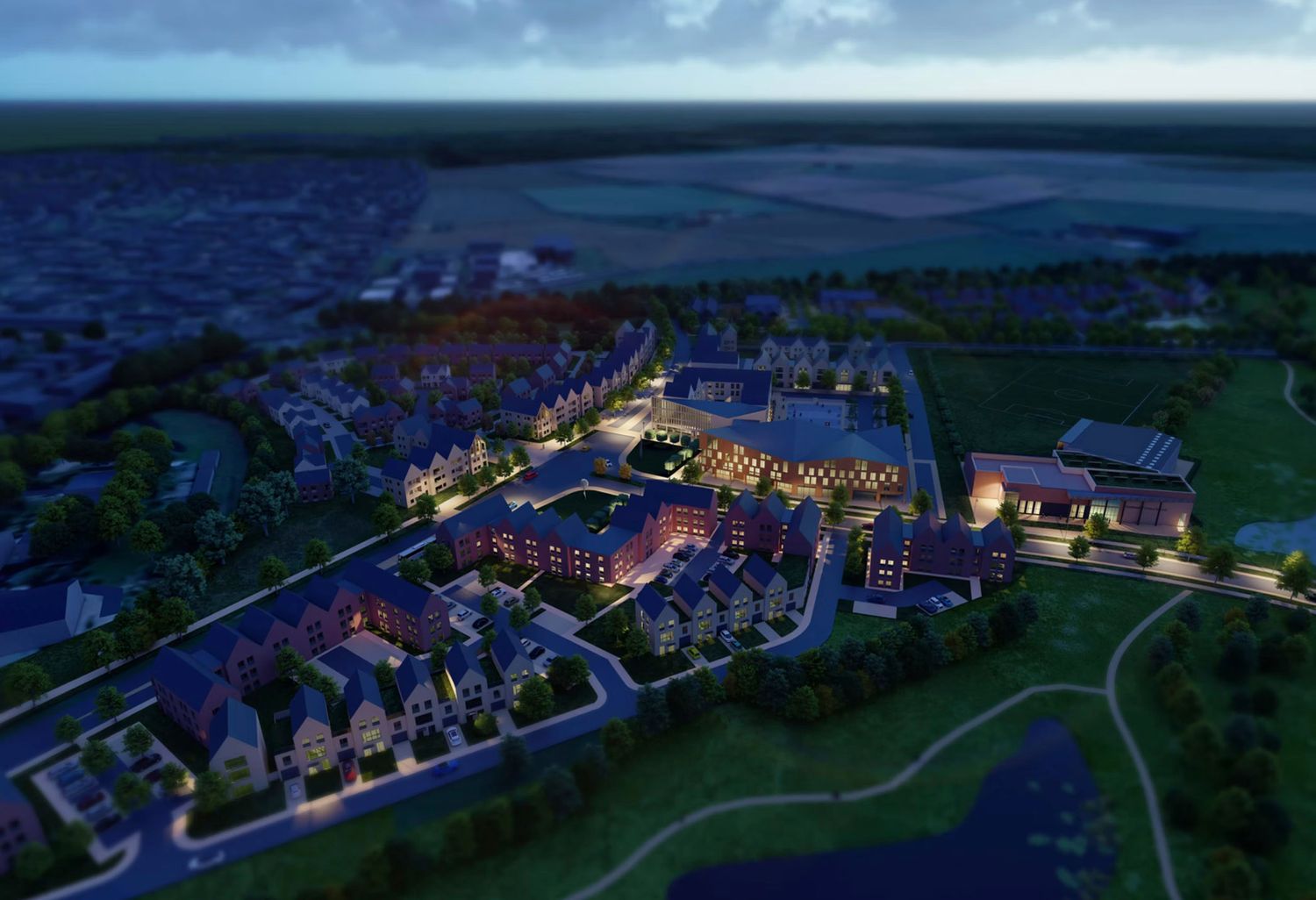 Aerial dusk view of a modern mixed-use development with illuminated buildings, pathways, and landscaped grounds.