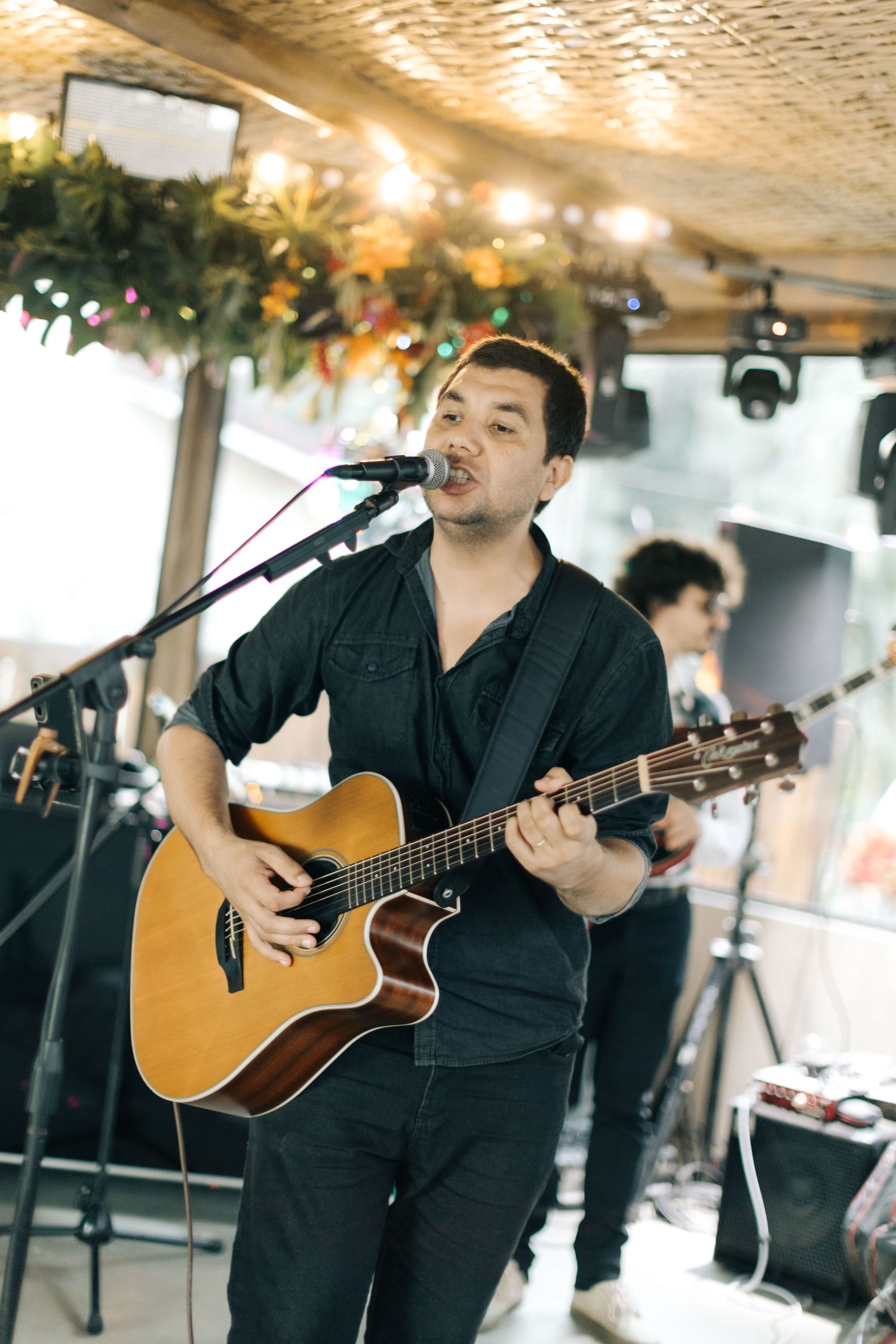 A musician performs with an acoustic guitar during a wedding reception under warm lighting.