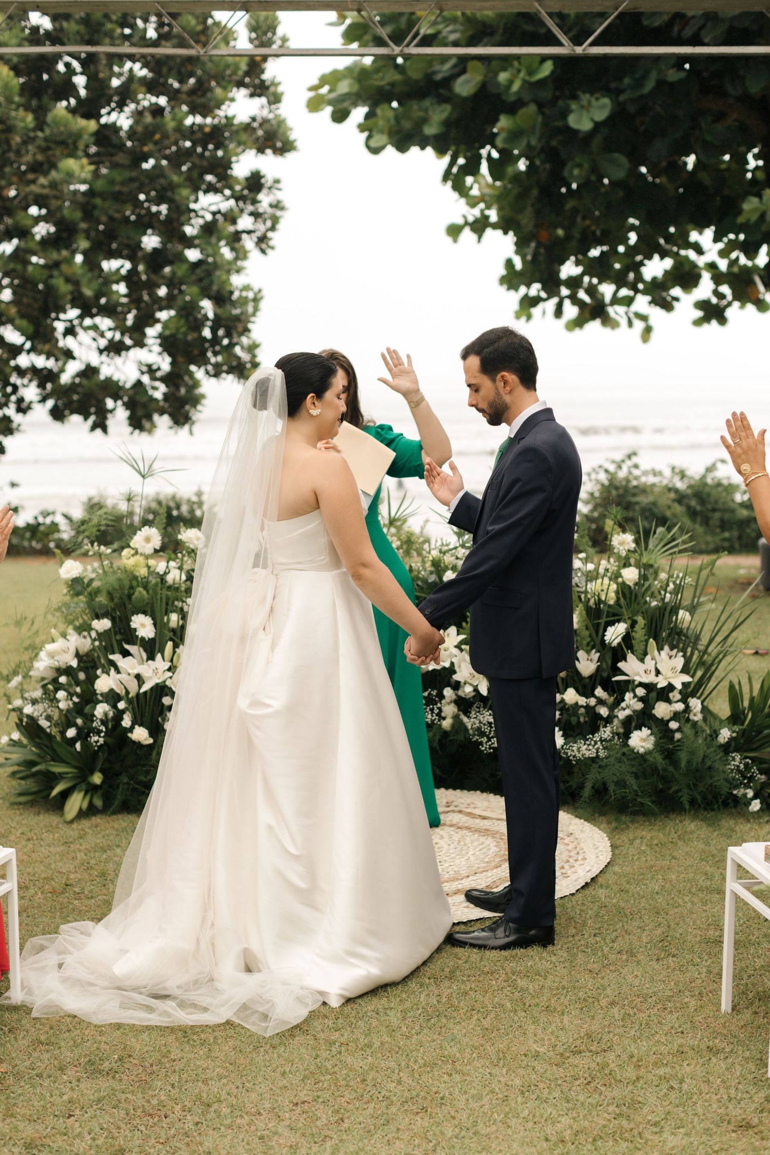 Wedding couple celebrating during their outdoor garden ceremony surrounded by white flowers.