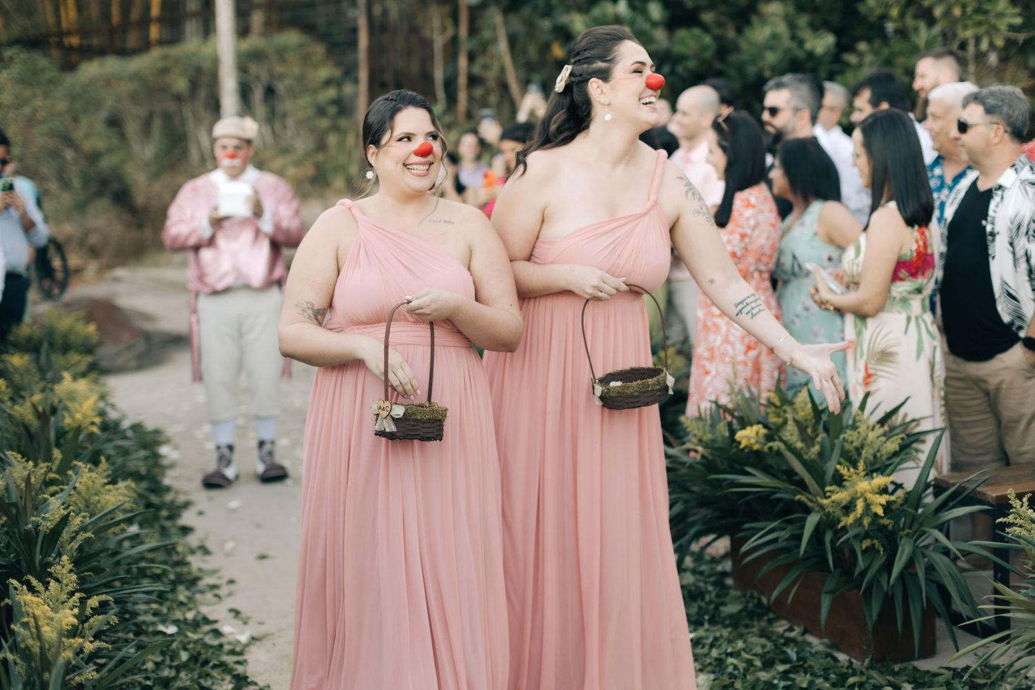 Wedding guests in pink dresses enjoying outdoor celebration.