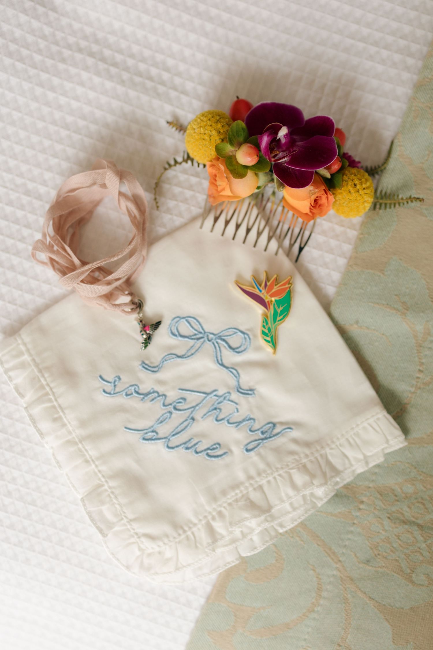 Embroidered handkerchief with blue text decorated with colorful floral accents and lace trim.