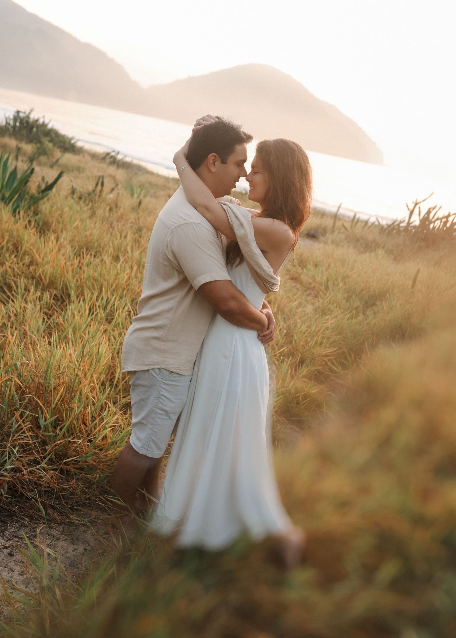 Two people share an intimate moment in a golden field at sunset.
