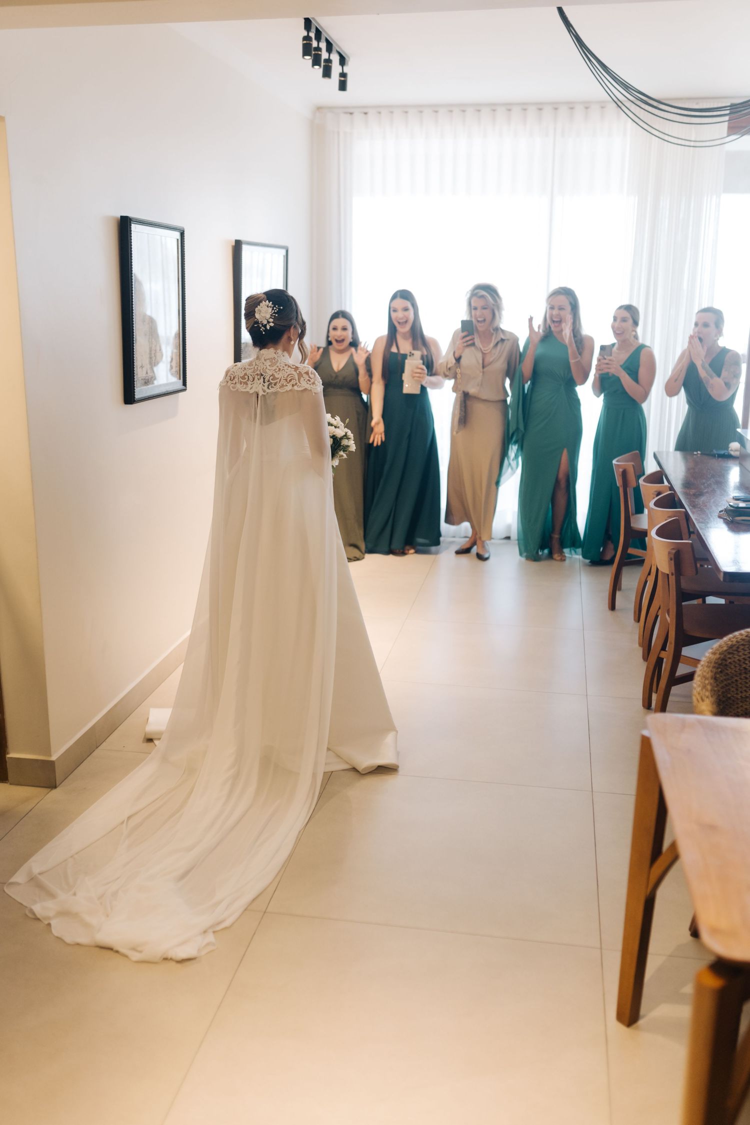 Wedding dress reveal with bridesmaids in emerald green dresses watching from behind.