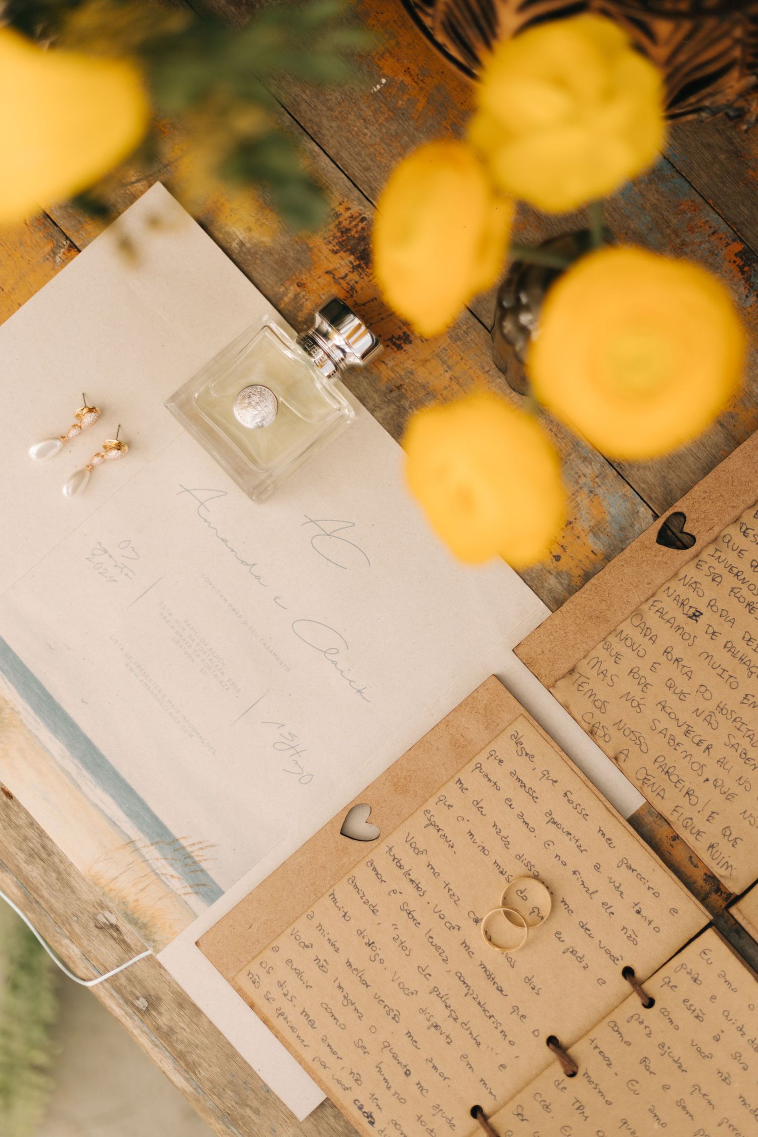 Wedding stationery and rings arranged on rustic wood with golden bokeh effect.