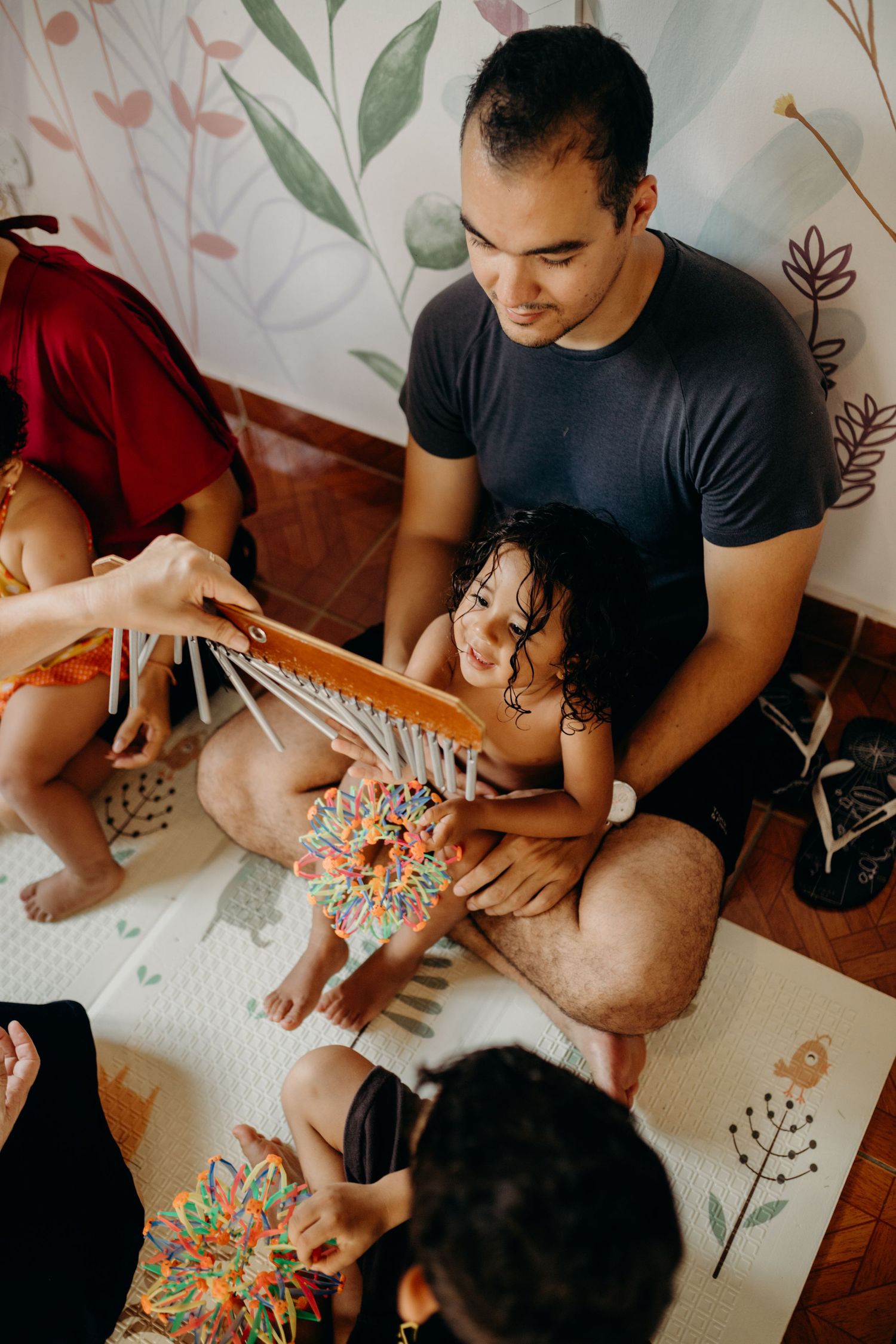 A joyful music session with chimes and colorful toys on a floral-patterned mat.