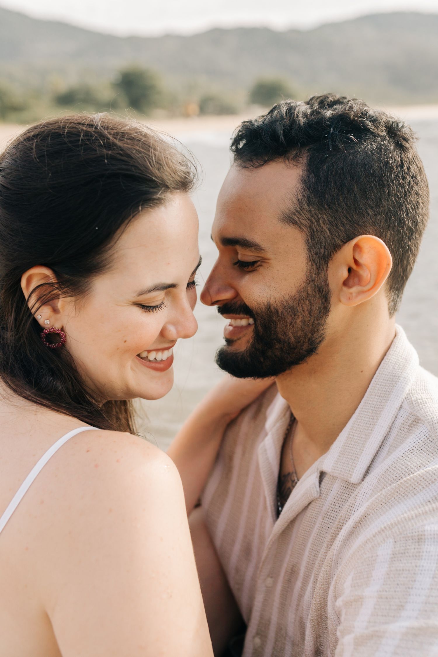 An intimate beach photoshoot featuring a couple in white attire.