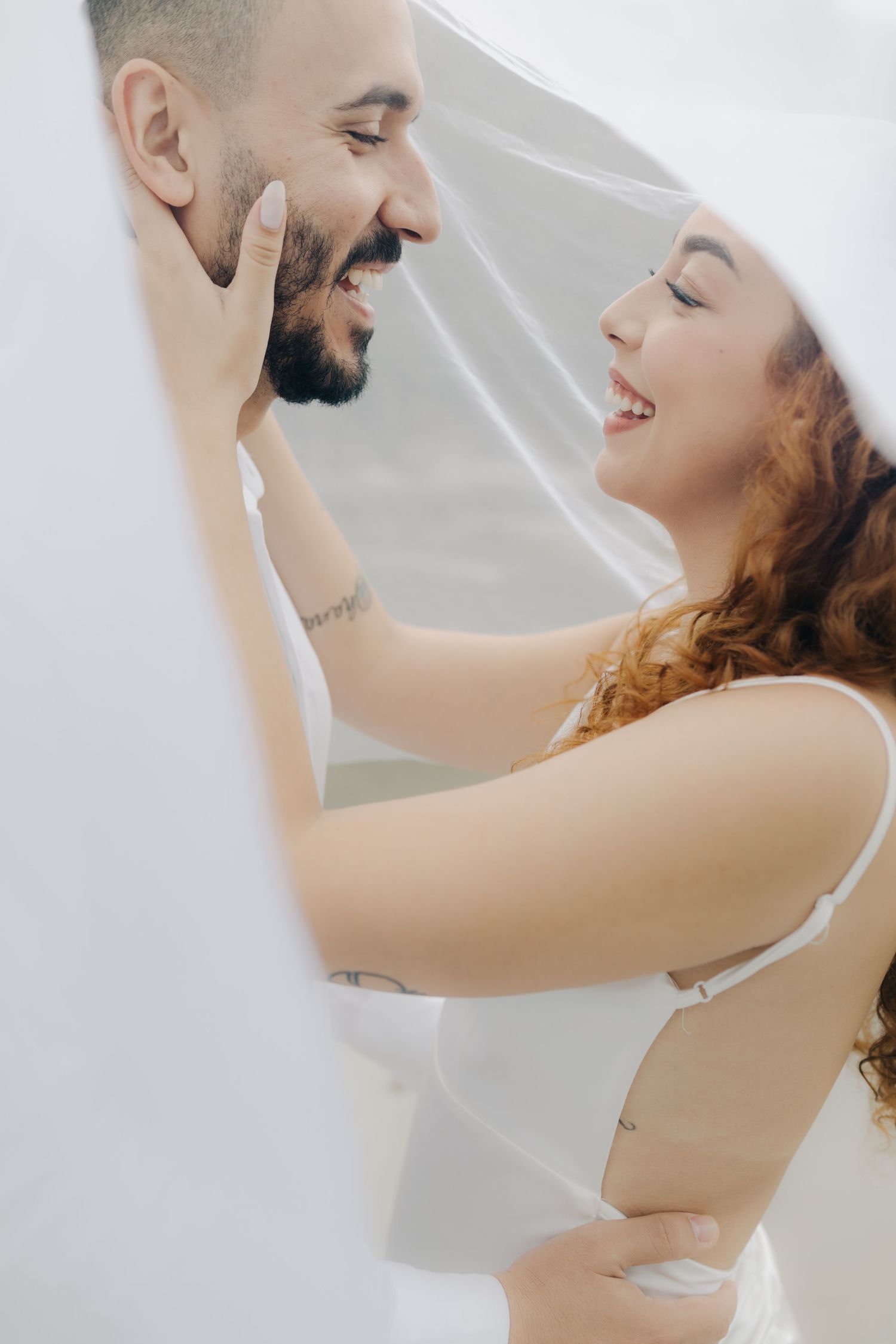 Intimate wedding portrait with couple sharing tender moments under flowing veil.
