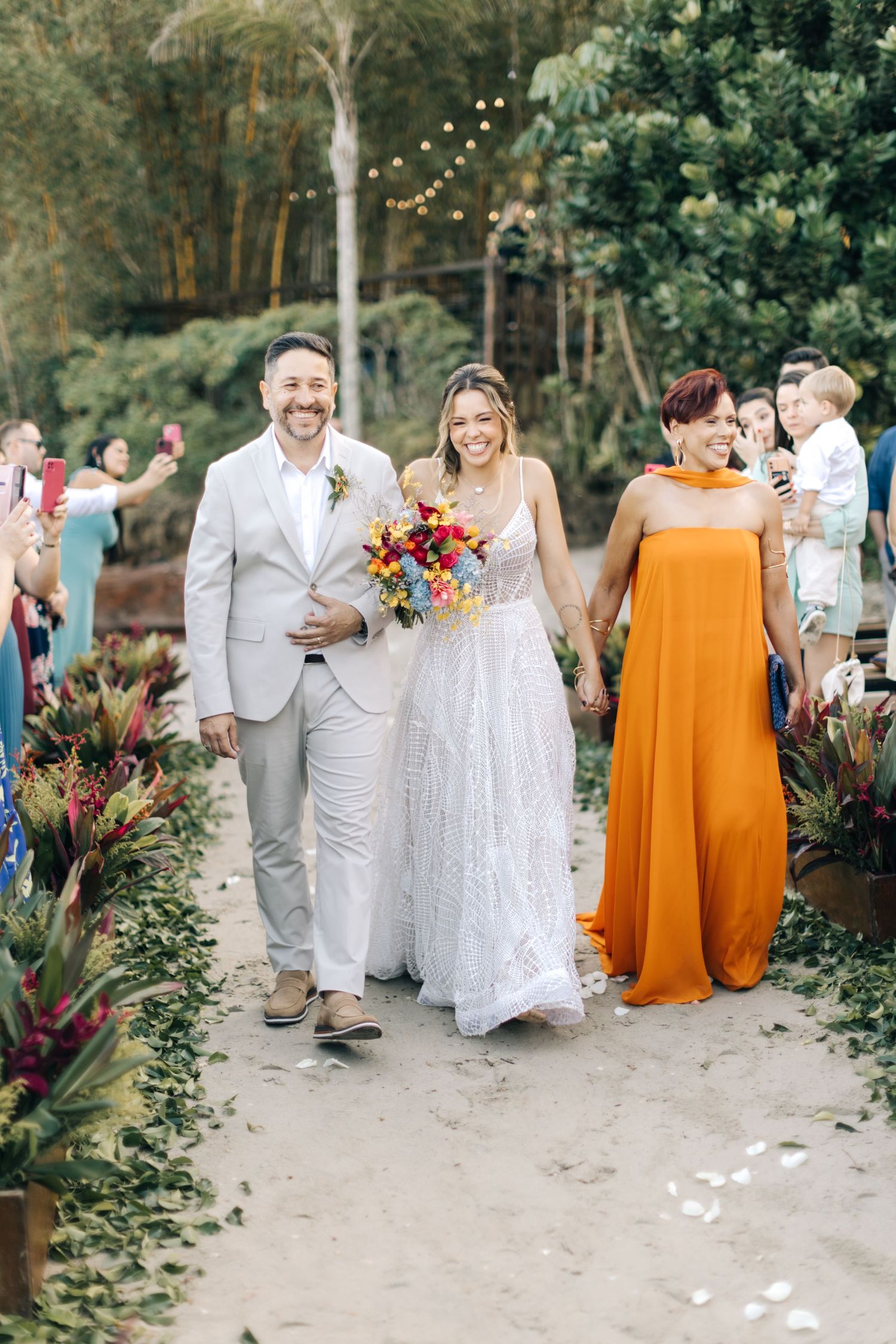 A joyful moment at an outdoor wedding ceremony with beautiful floral decor and string lights overhead.