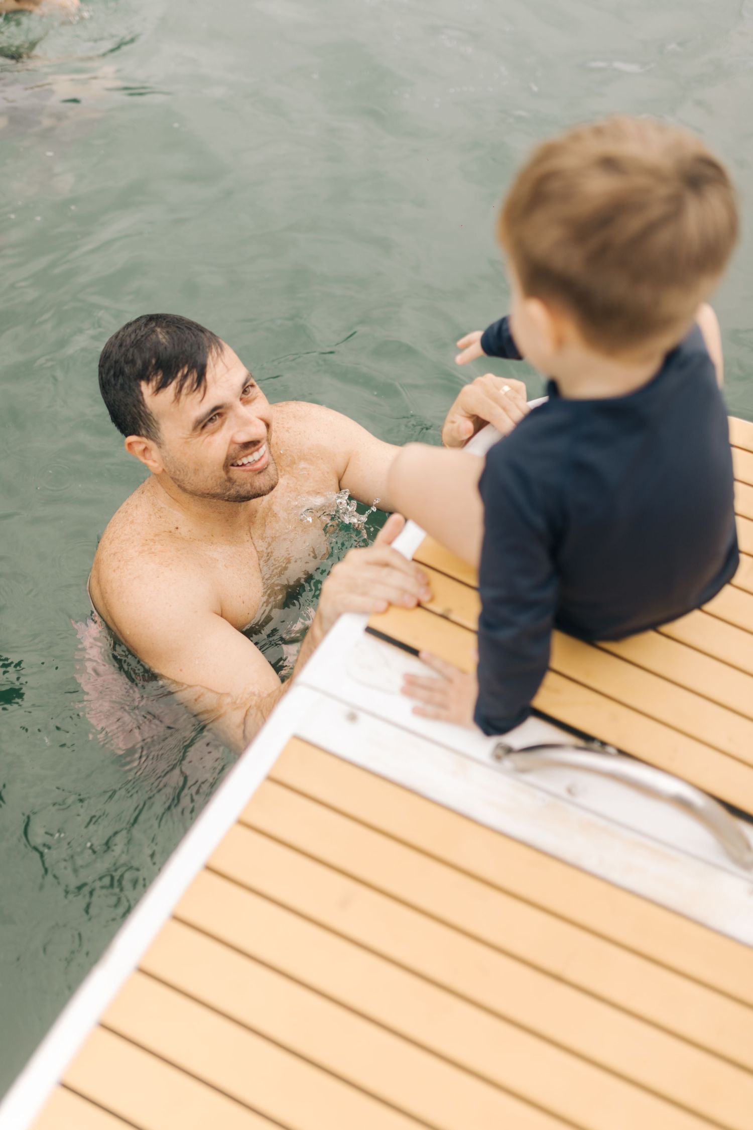 Sweet moment between parent and child on boat deck after swimming in ocean.