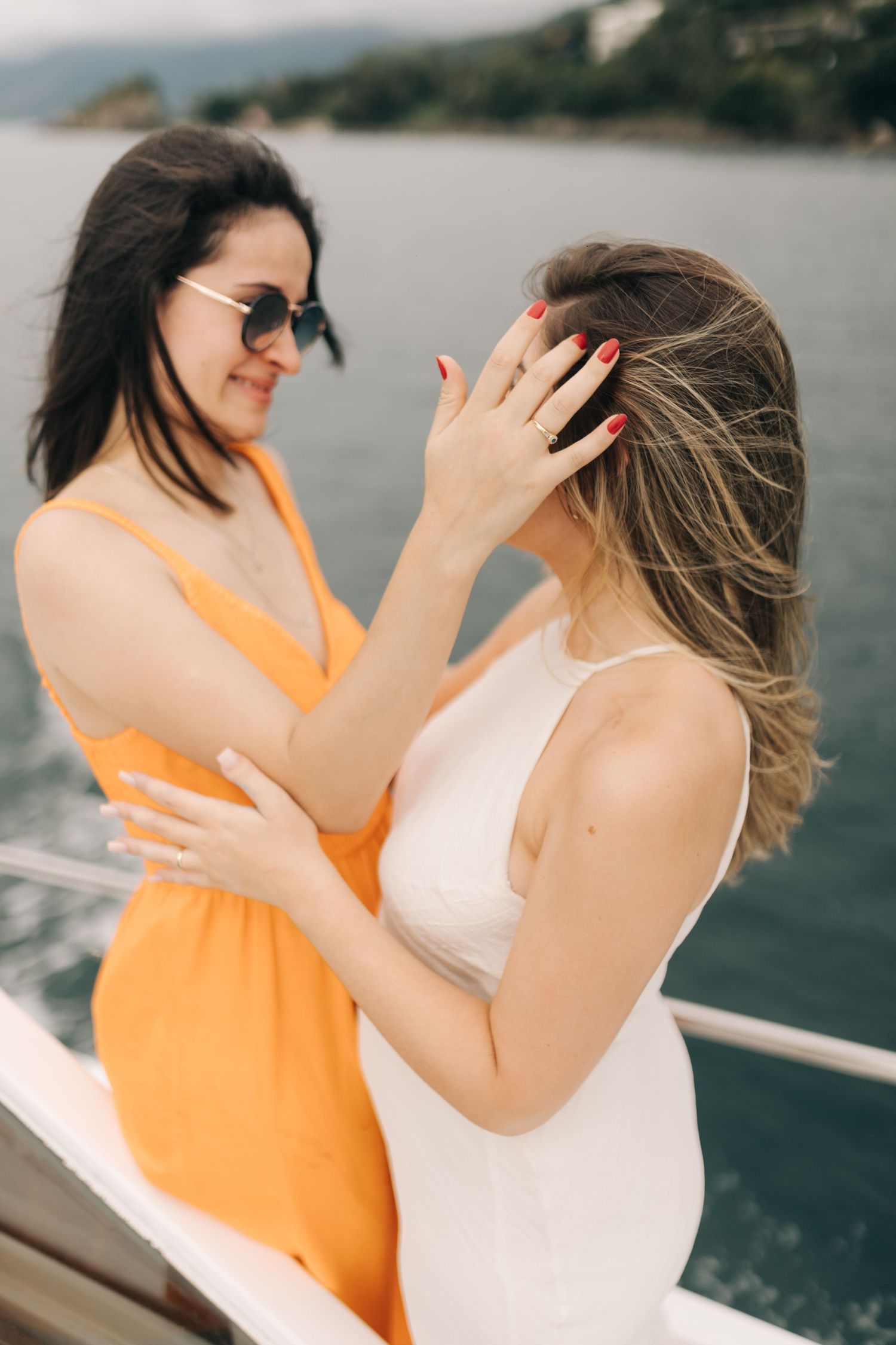 Playful friends in orange and white outfits dancing on a boat deck.