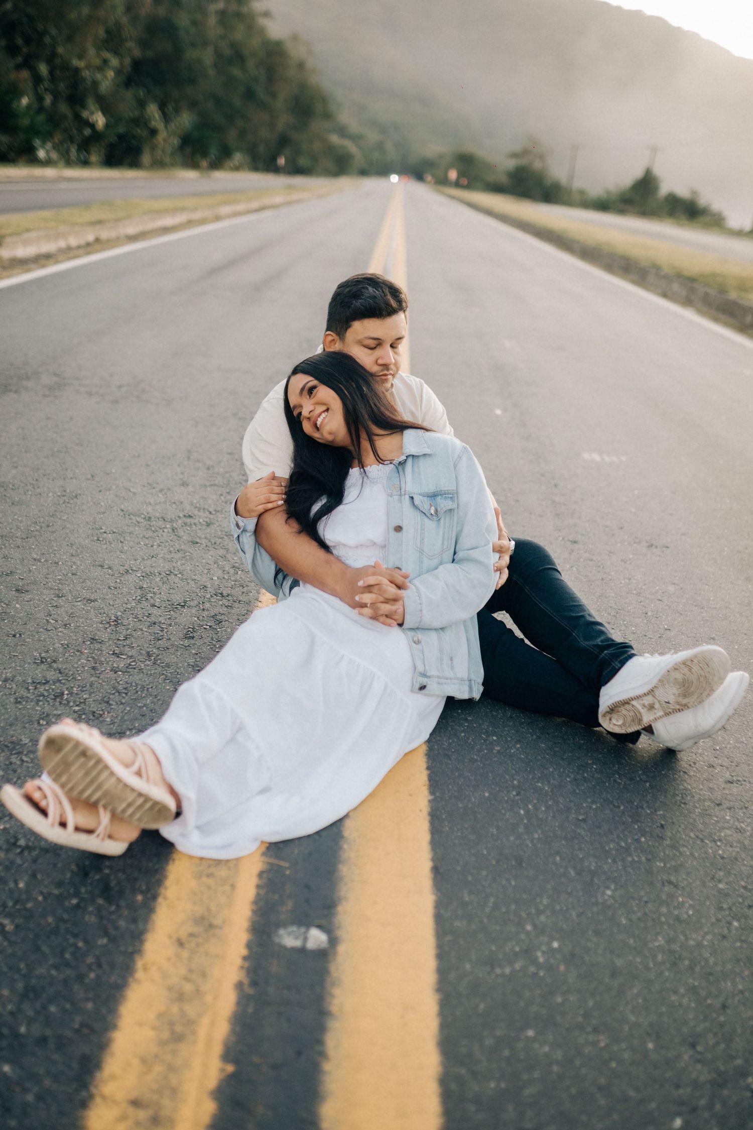 Playful couple posing on road with yellow dividing lines.