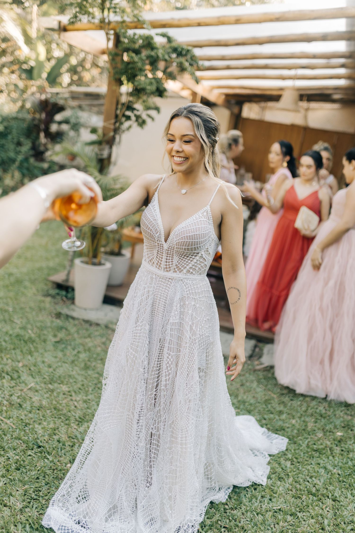 A person in a delicate white lace wedding gown shares a joyful moment during an outdoor celebration.