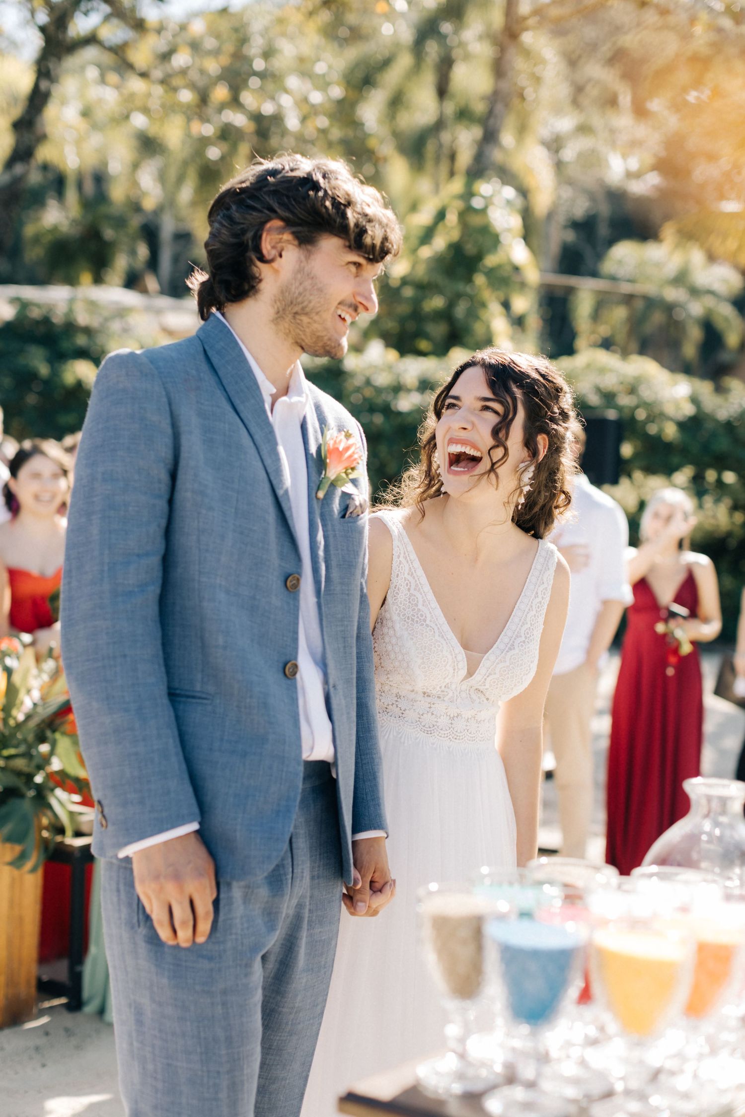 Couple shares laughs during their outdoor wedding with colorful drinks displayed.