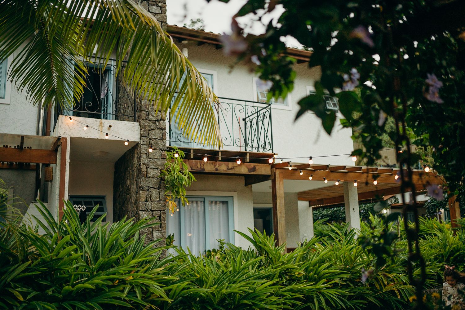 Tropical resort balcony with palm trees and wooden pergola details in natural lighting.