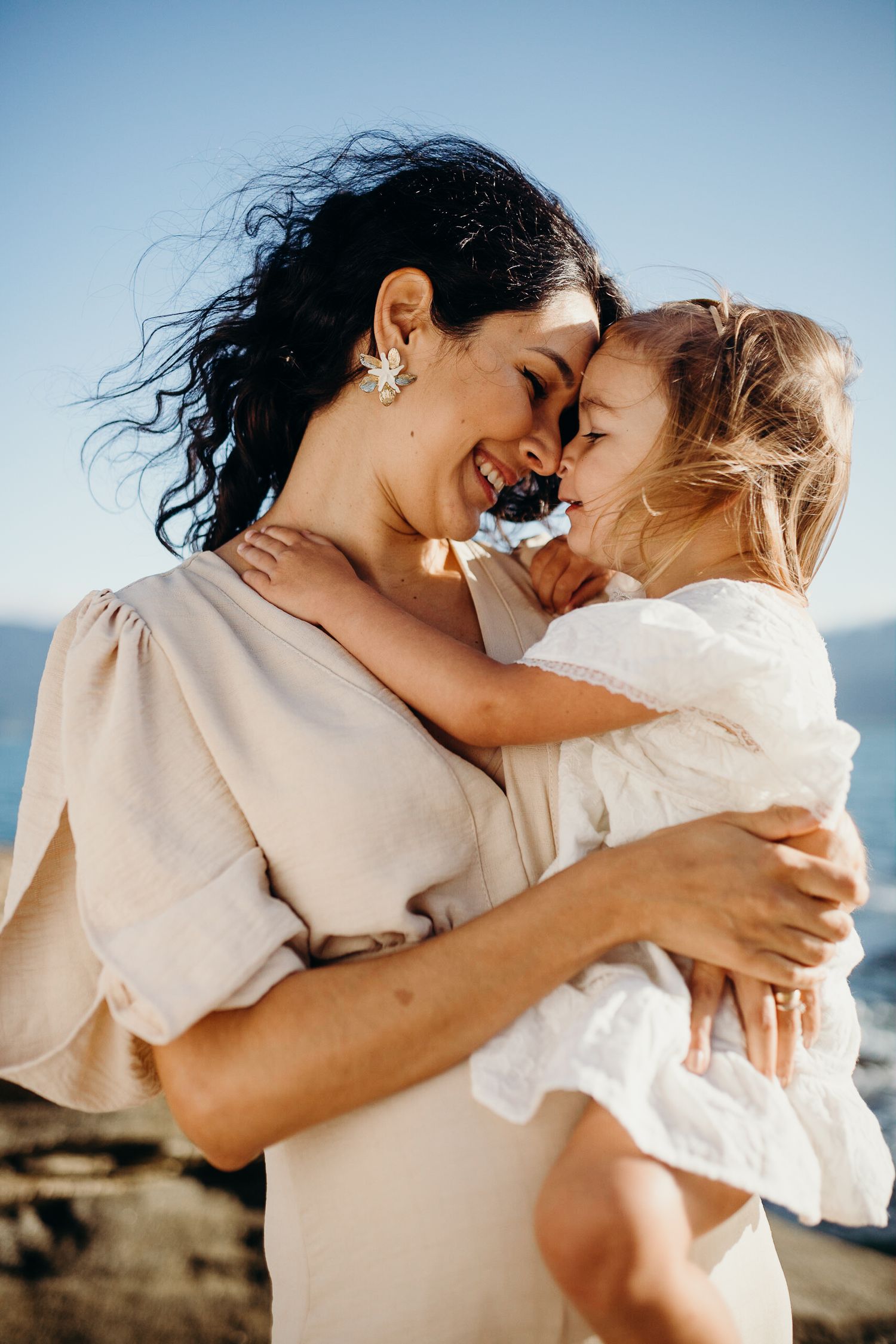 Candid moment of parent and child sharing laughter on rocky beach.