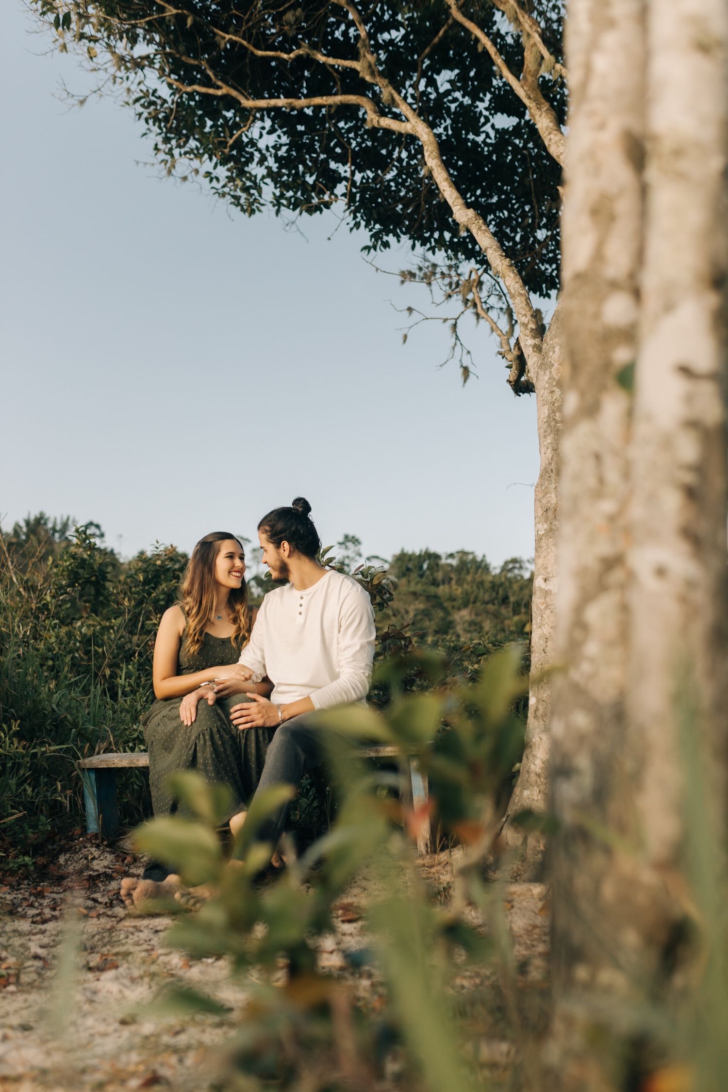 Romantic moment captured through tree branches in a natural outdoor setting.