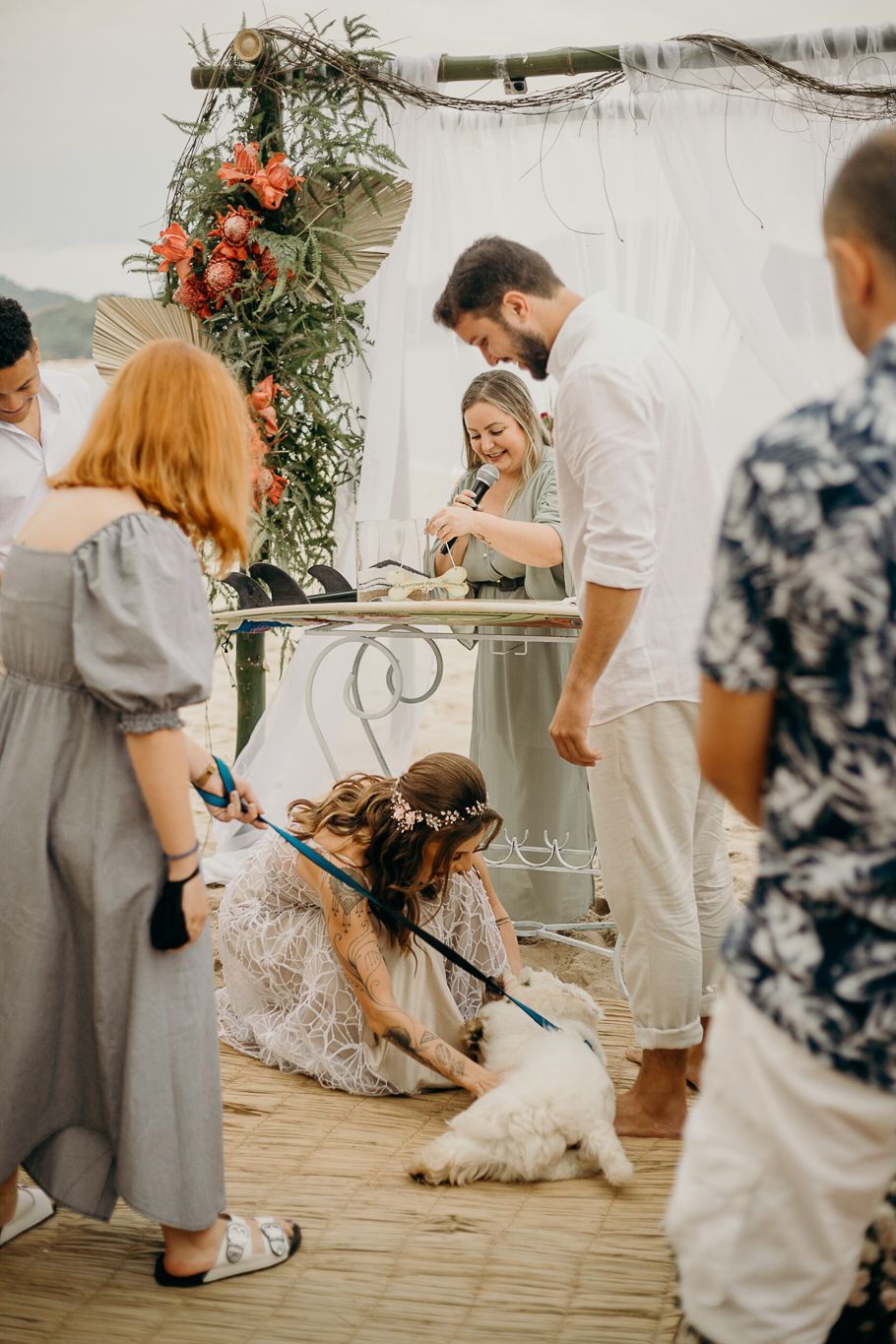 Wedding ceremony setup with floral arch and guests gathered around on a wooden deck.