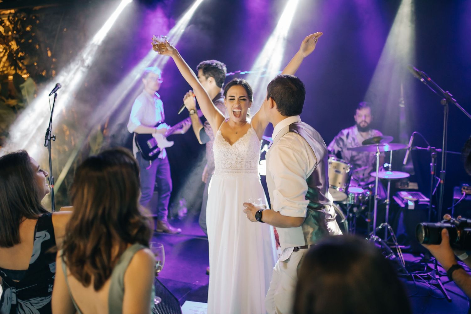 Couple dancing under dramatic purple stage lighting with a live band performing in the background.