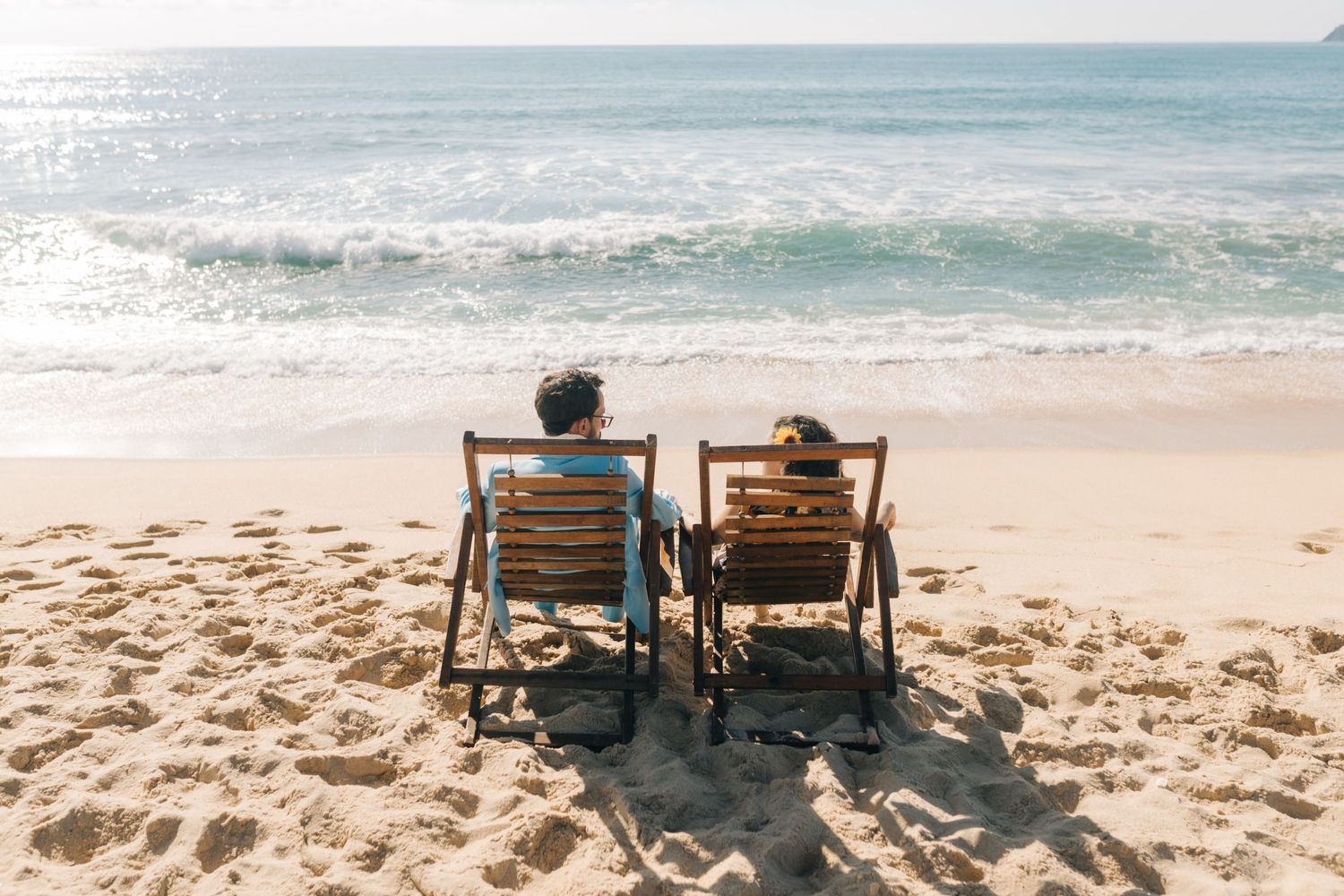 Two people sitting in beach chairs watching the ocean waves.