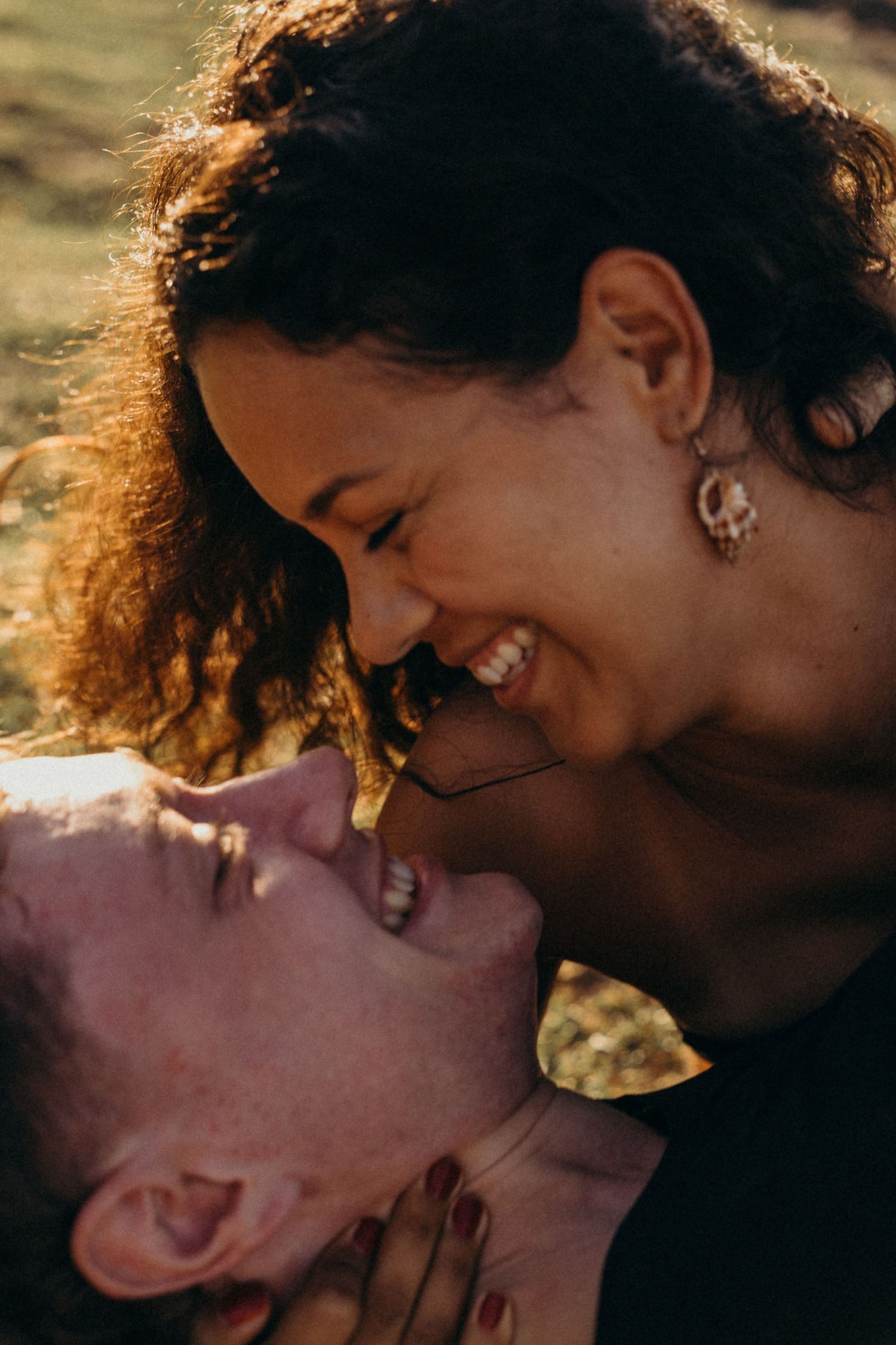 Intimate close-up of couple sharing laughter and joy in warm sunlight.