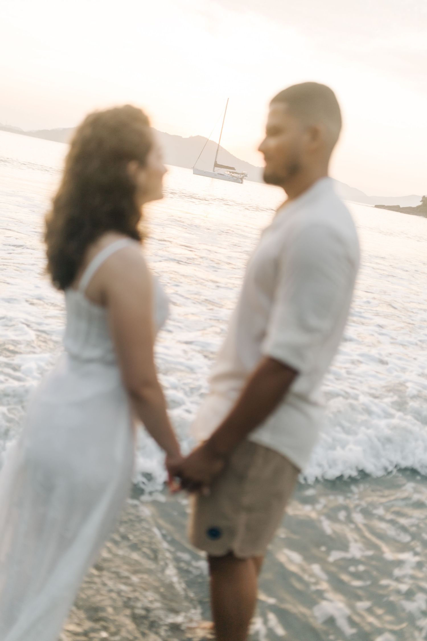 Romantic couple standing in the ocean waves during sunset.