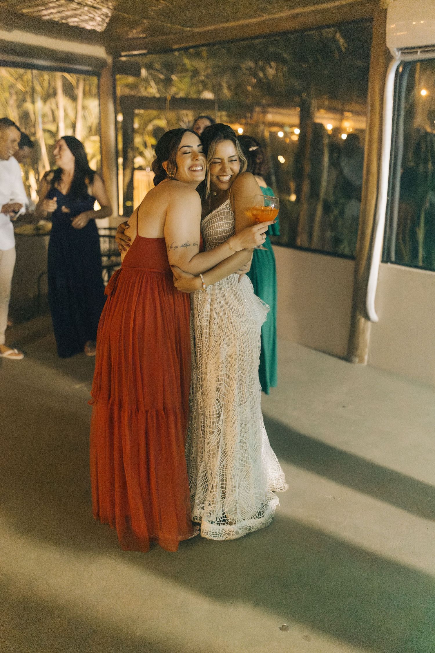 Wedding reception dance floor with guests in colorful dresses celebrating under warm lighting.