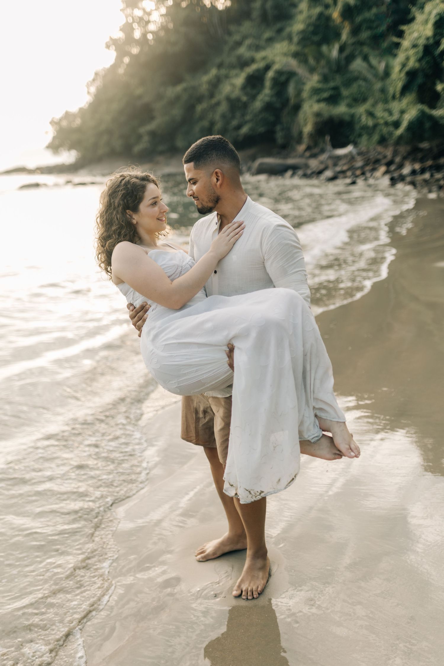Playful couple dancing and twirling together on a scenic beach at sunset.