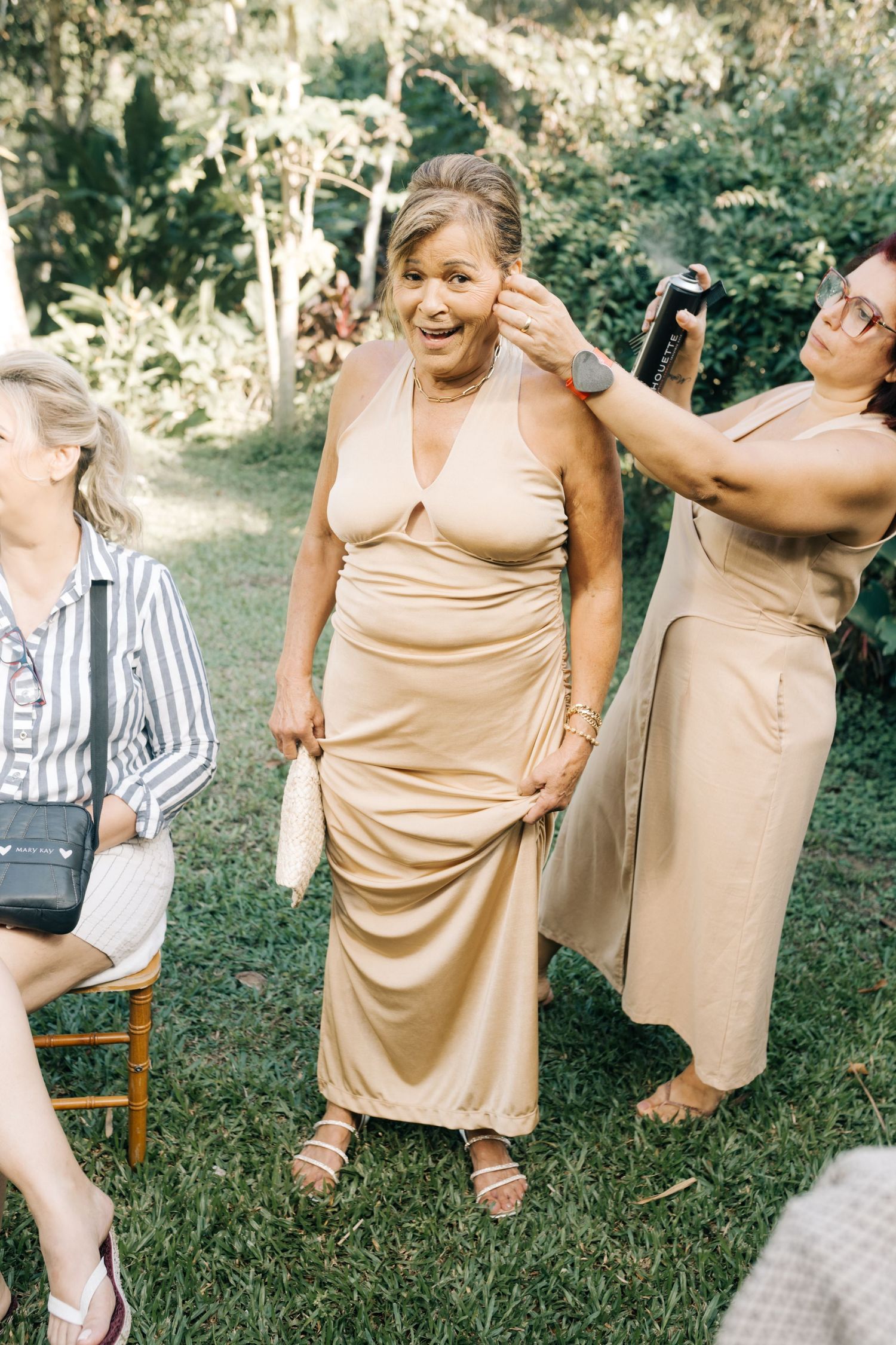 Wedding party members in champagne-colored dresses sharing a joyful moment outdoors.