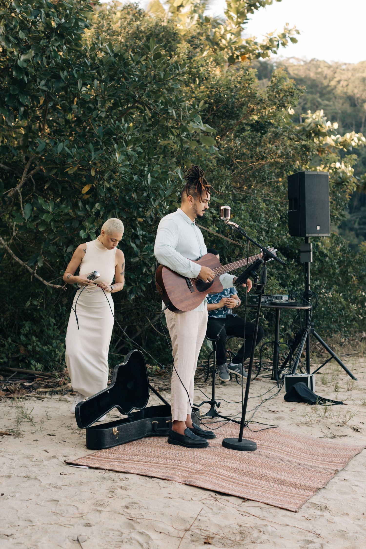 Musicians performing on rugs during outdoor wedding ceremony.