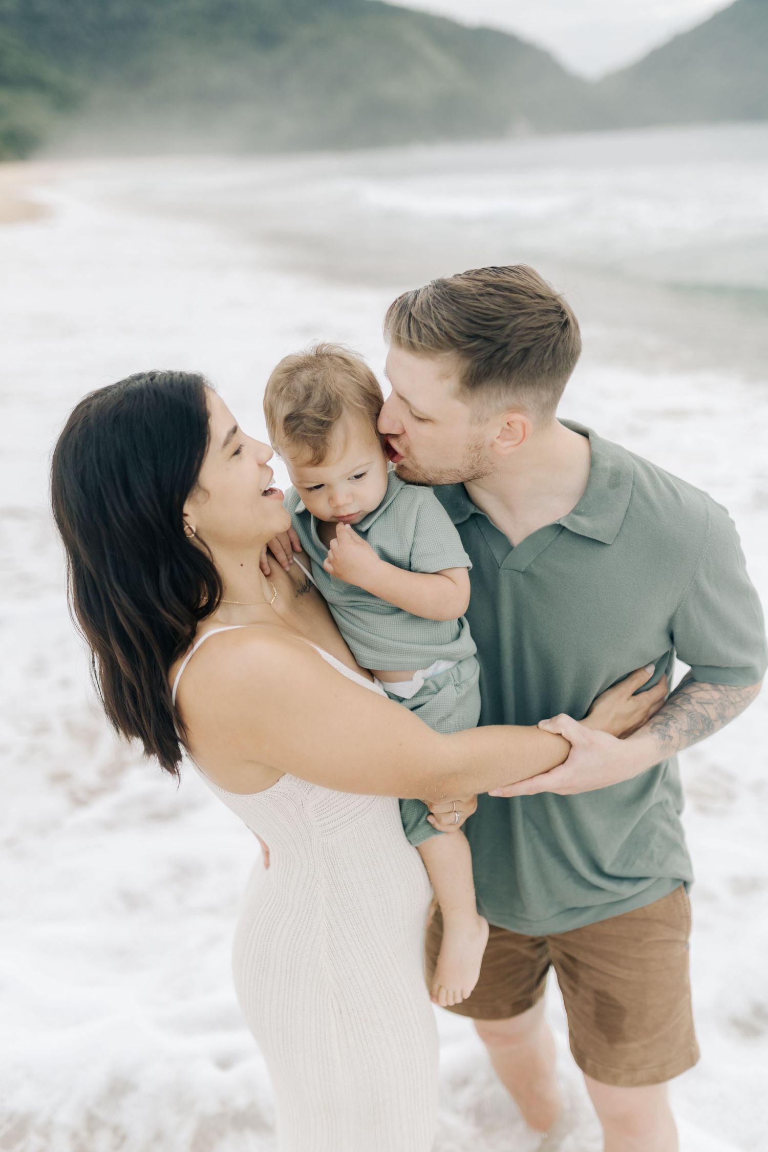 A loving family embraces each other on a misty beach during a photo session.