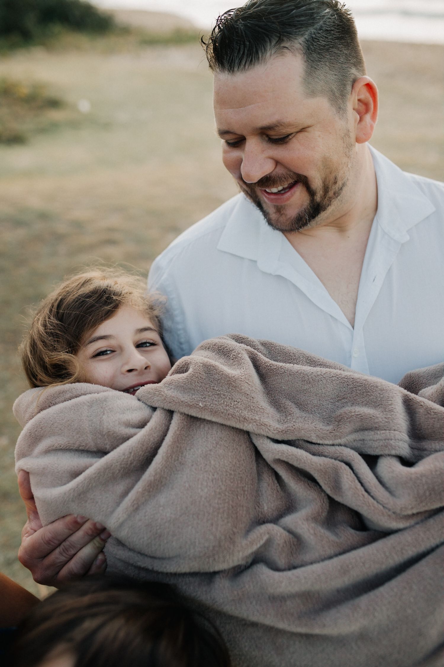 Intimate family portrait showing tender moments and warm embraces at golden hour.