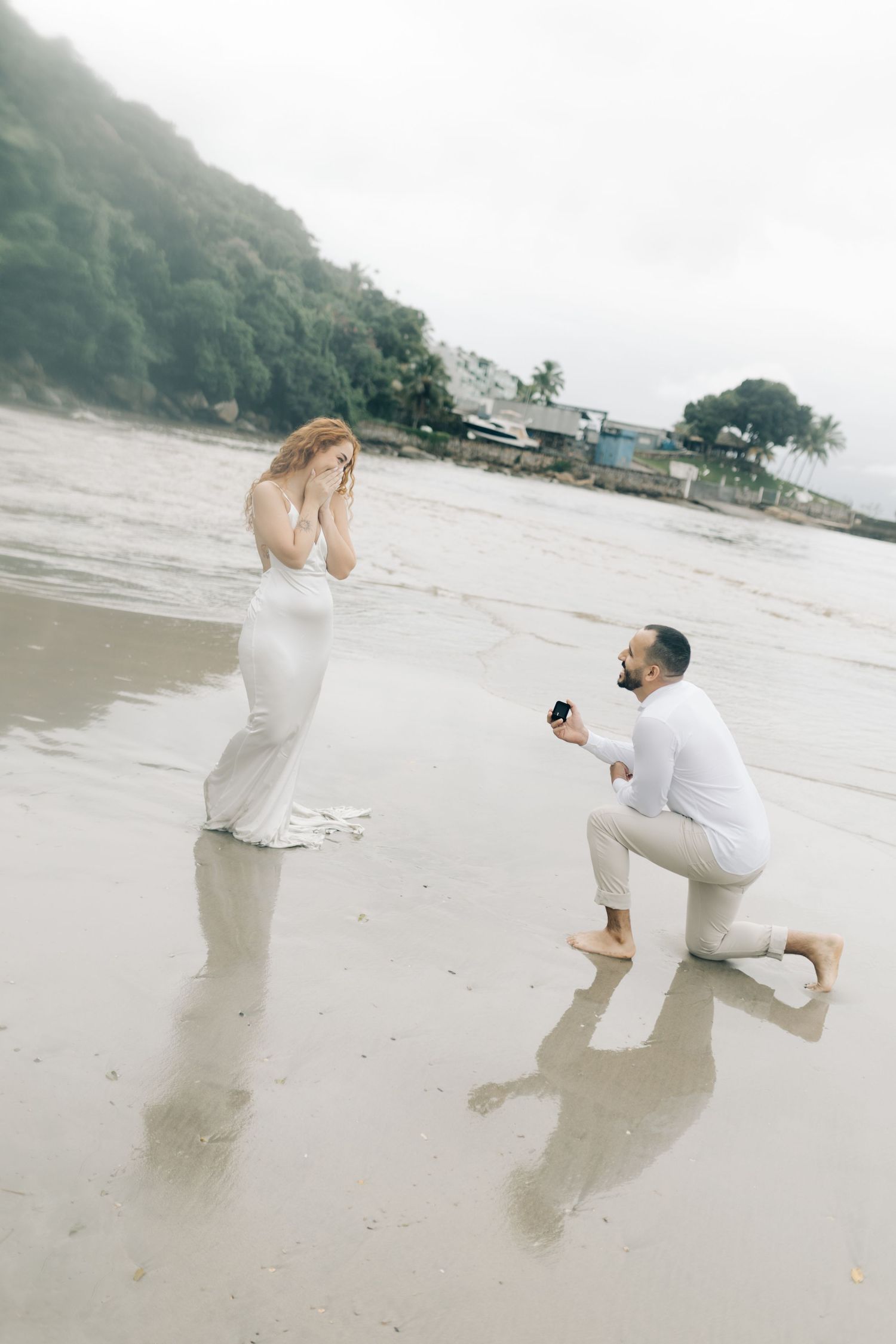 Candid proposal reaction on misty beach with emotional response.
