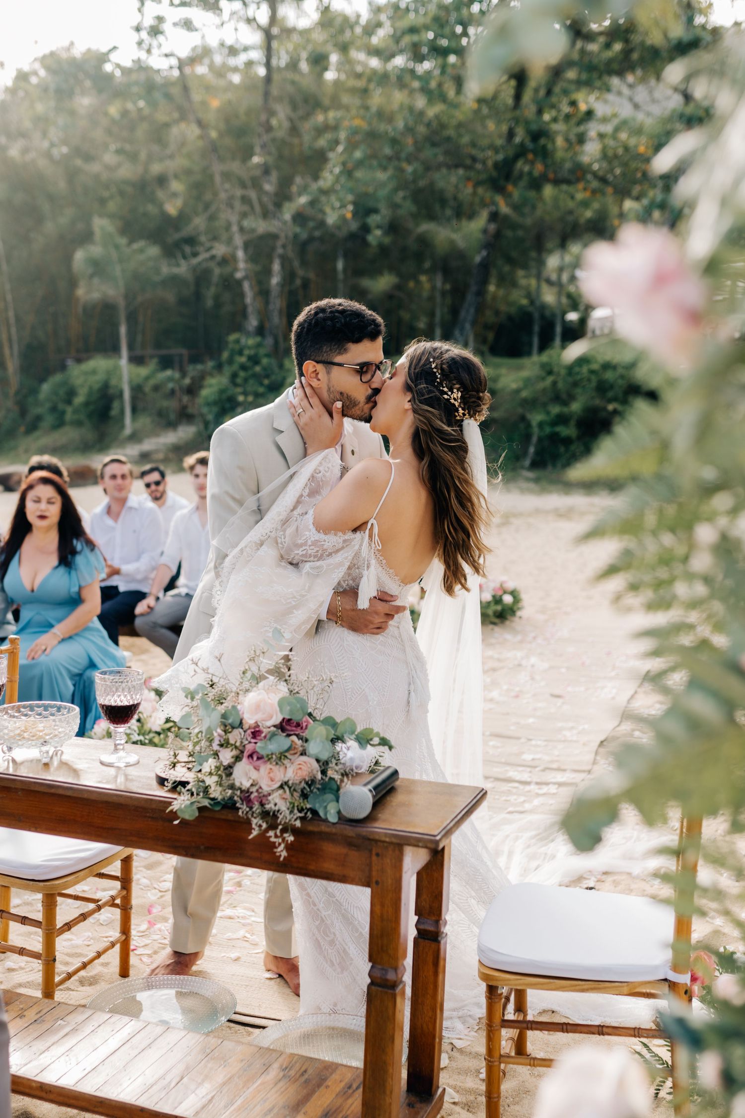 Romantic moment shared on wooden table during outdoor wedding reception.