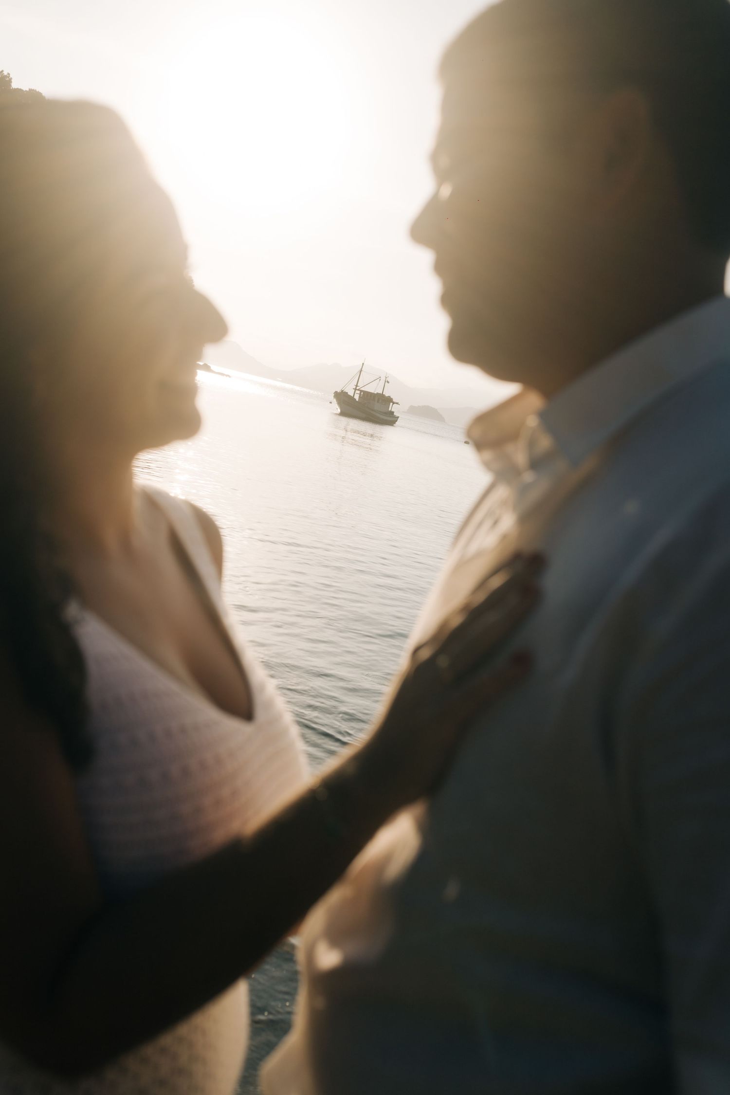 Backlit silhouettes of couple against ocean backdrop during golden hour.