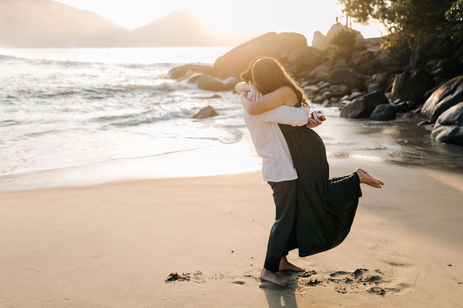Celebratory lift on the beach after a romantic sunset proposal.