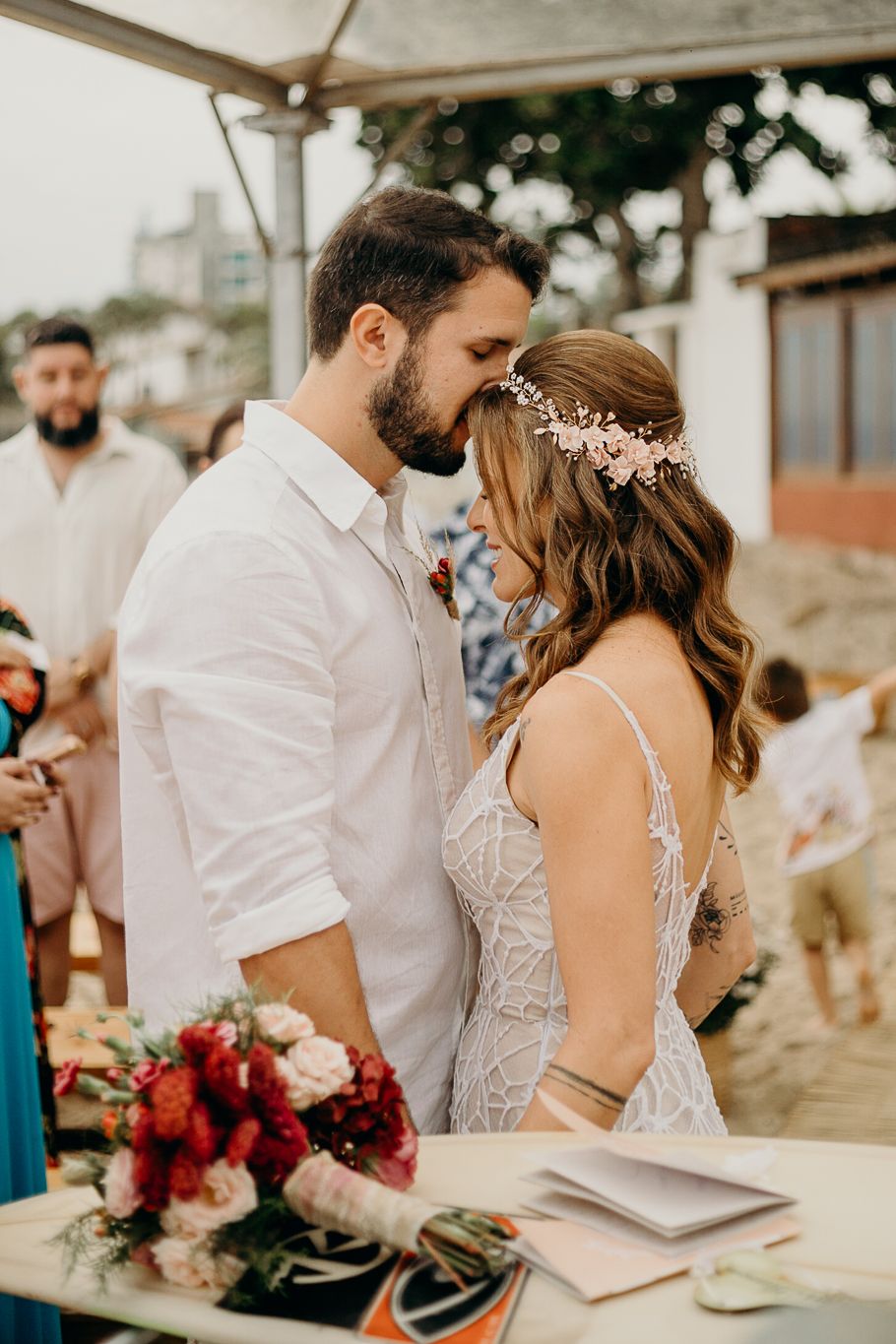 Intimate wedding ceremony moments shared between couple at beach venue with floral arrangements.