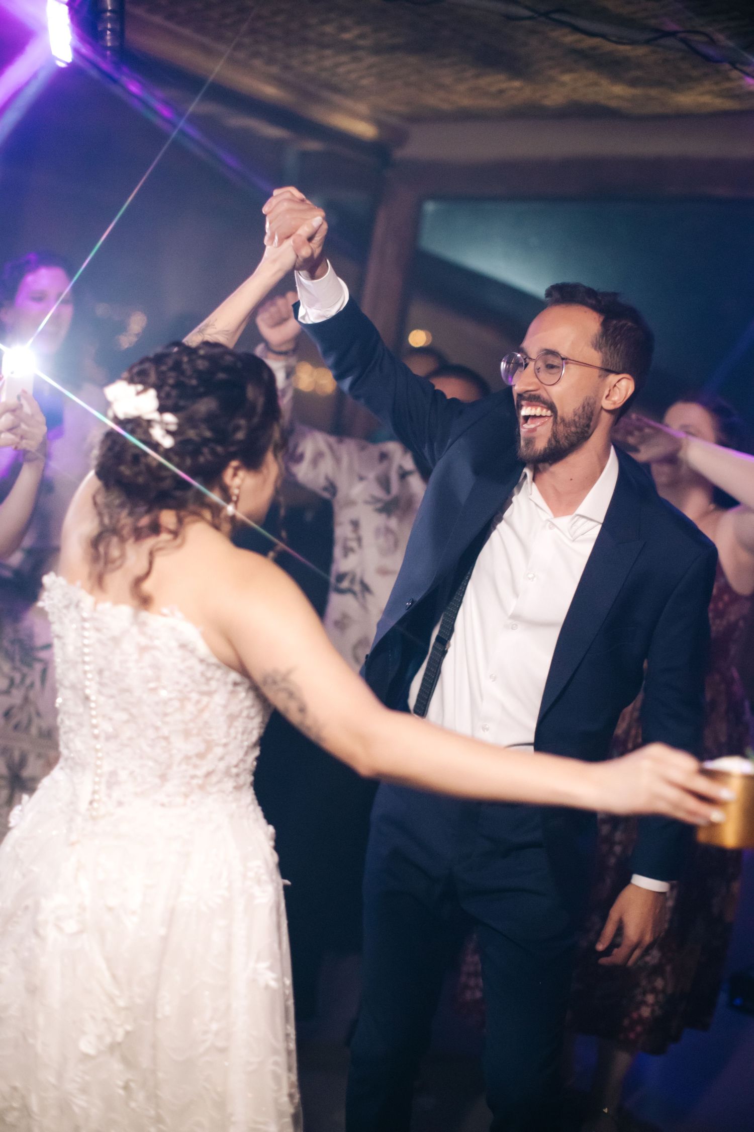A joyous dance celebration at a wedding reception with colorful lighting and festive atmosphere.