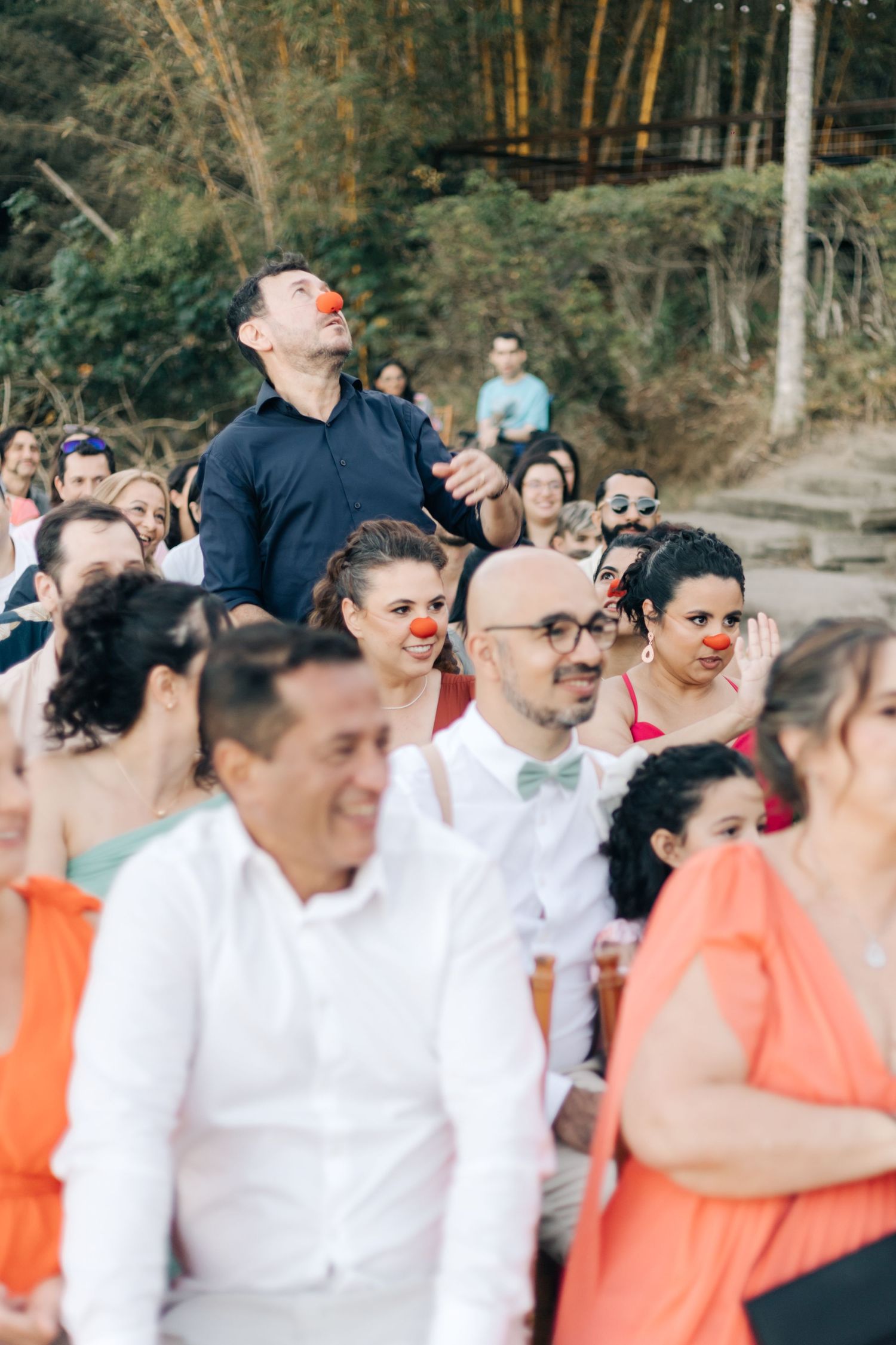 Wedding guests in coral and white attire gather outdoors during the celebration.