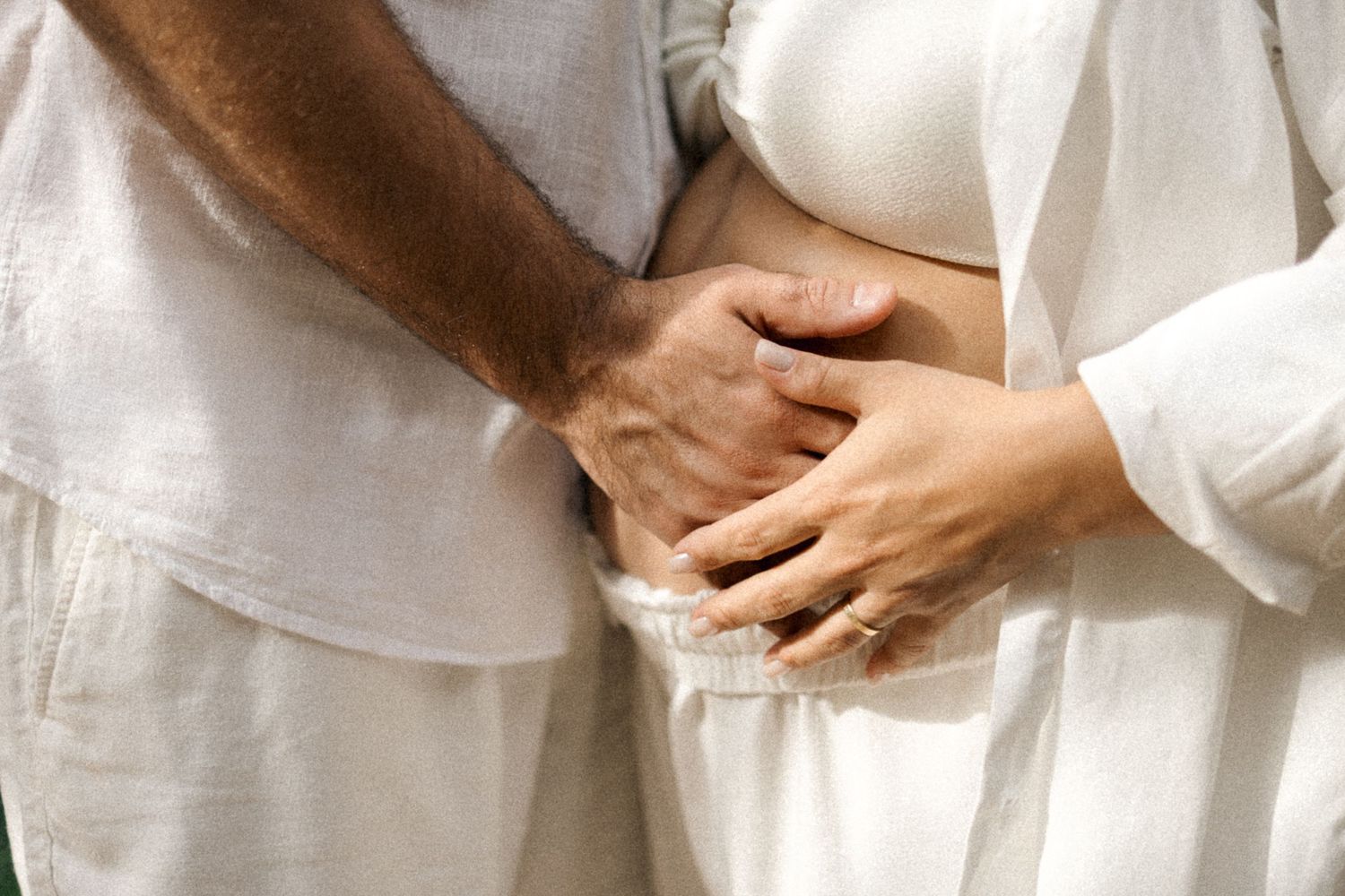 Group of people wearing white clothing hold hands in a circle during a spiritual or ceremonial gathering.
